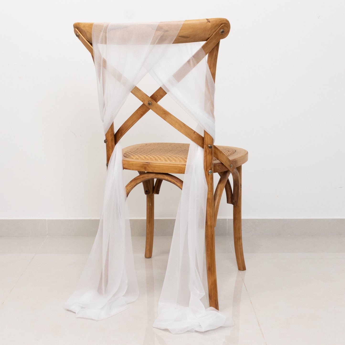 White sheer chair drape with 9ft shimmer sash on a wooden chair.