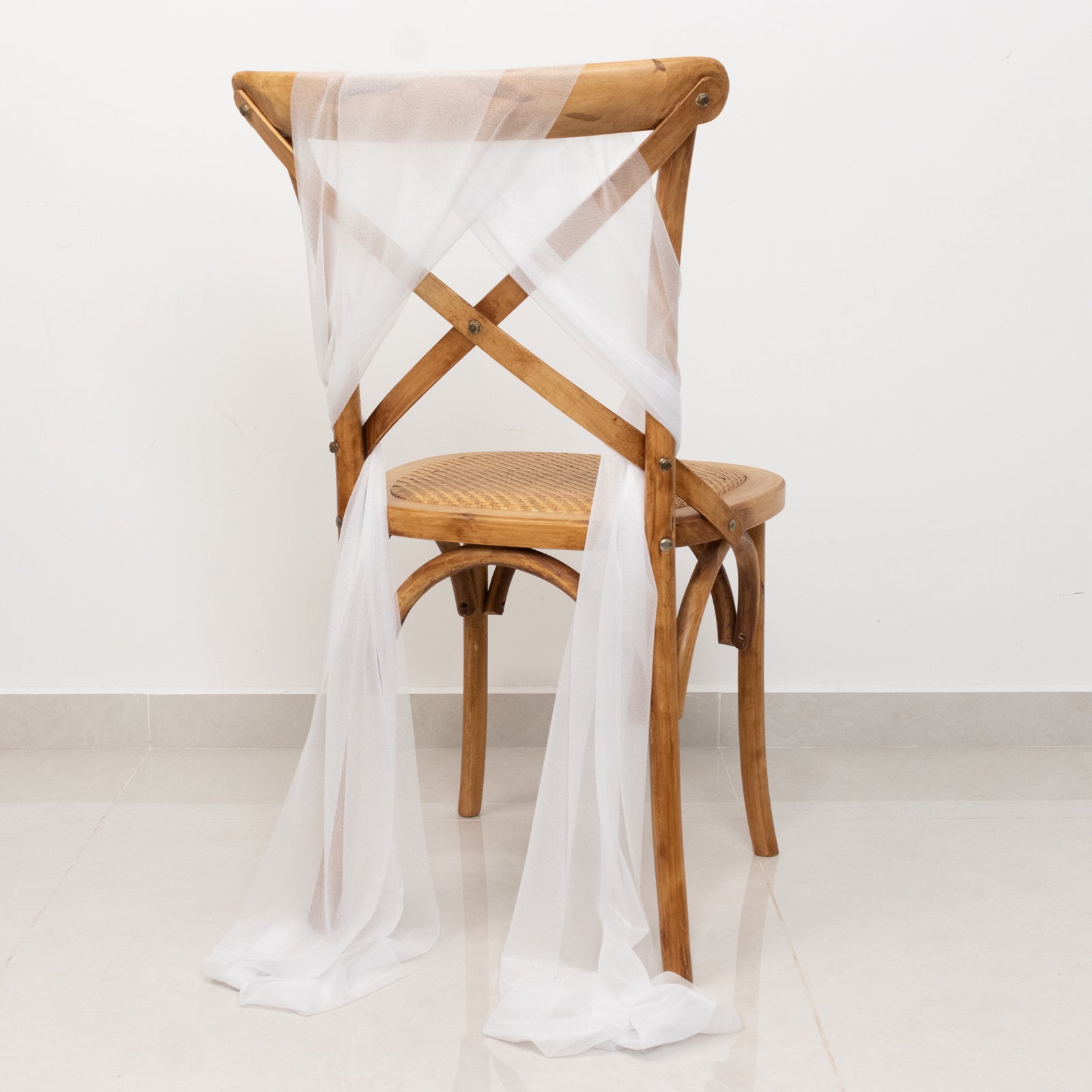 White sheer chair drape with 9ft shimmer sash on a wooden chair.