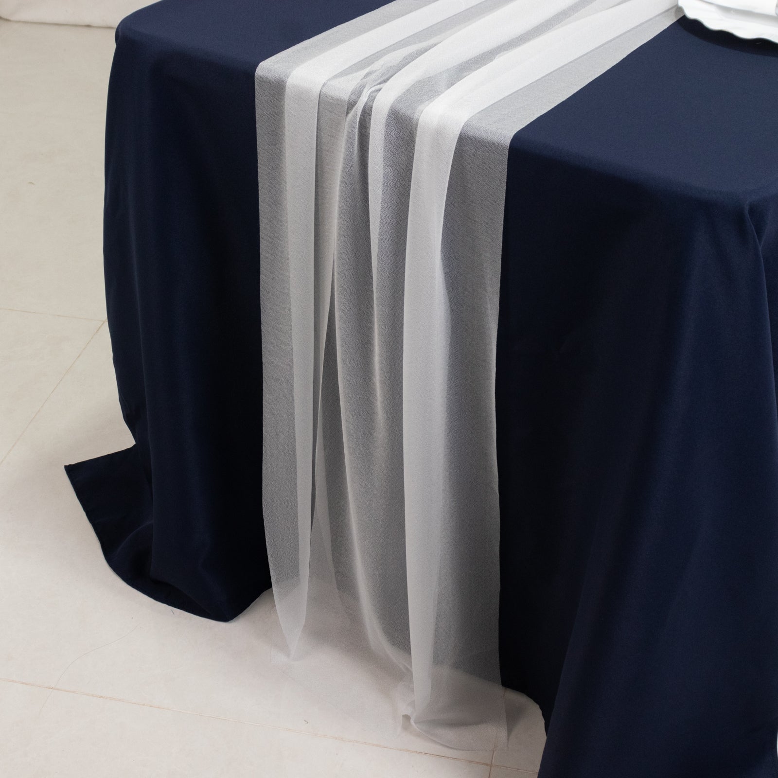 White shimmer sheer table runner on a navy blue table.