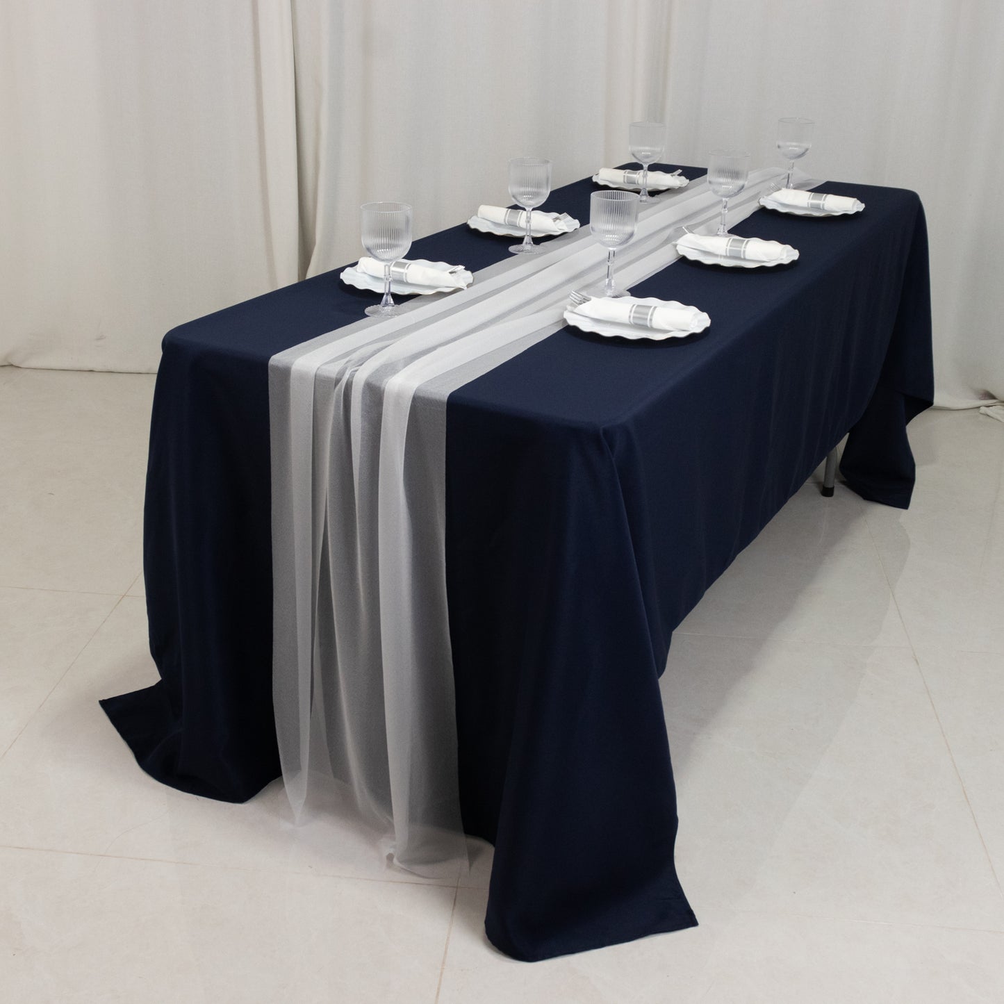 White sheer table runners on a navy blue table setting.