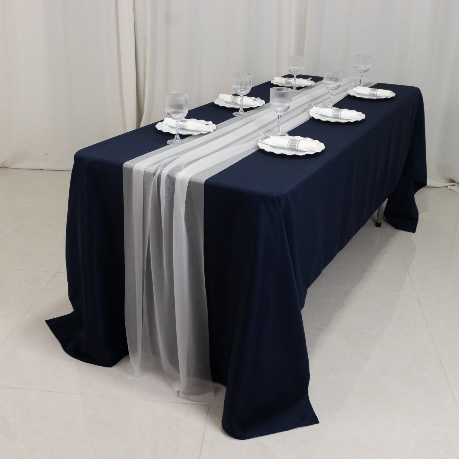 White sheer table runners on a navy blue table setting.