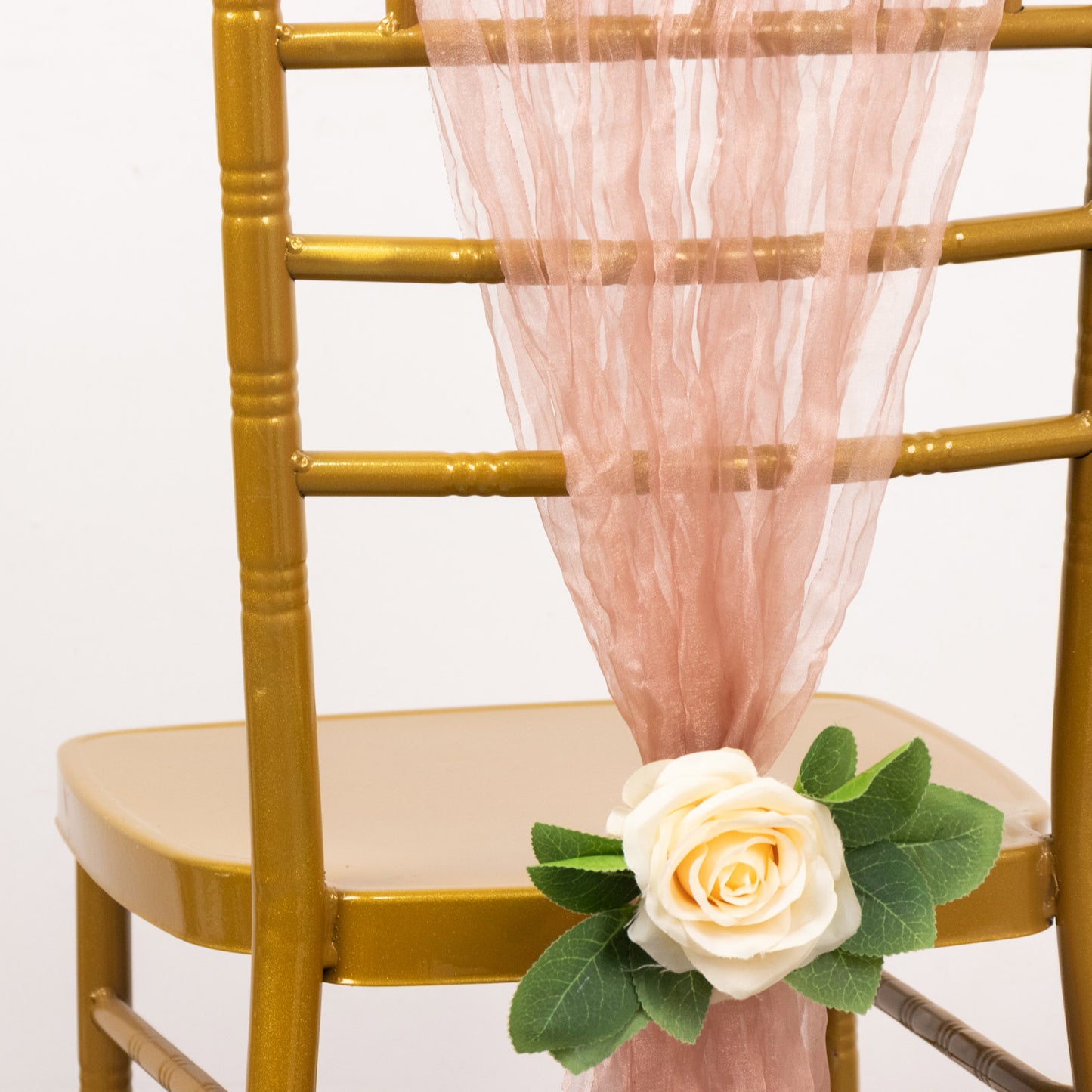 Dusty rose sheer crinkled organza chair sash draped on a gold chair.