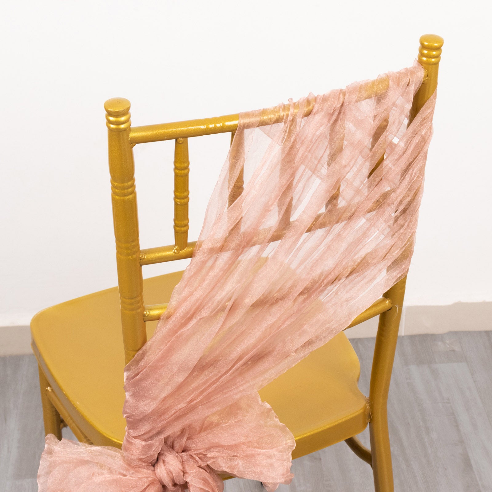 Dusty rose sheer crinkled organza chair sash on a gold chair.