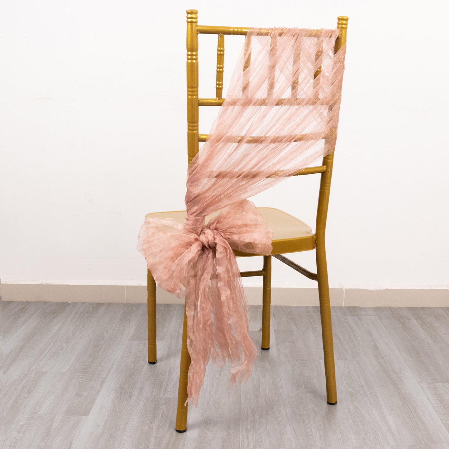 Dusty rose sheer crinkled organza chair sash on a gold chair.