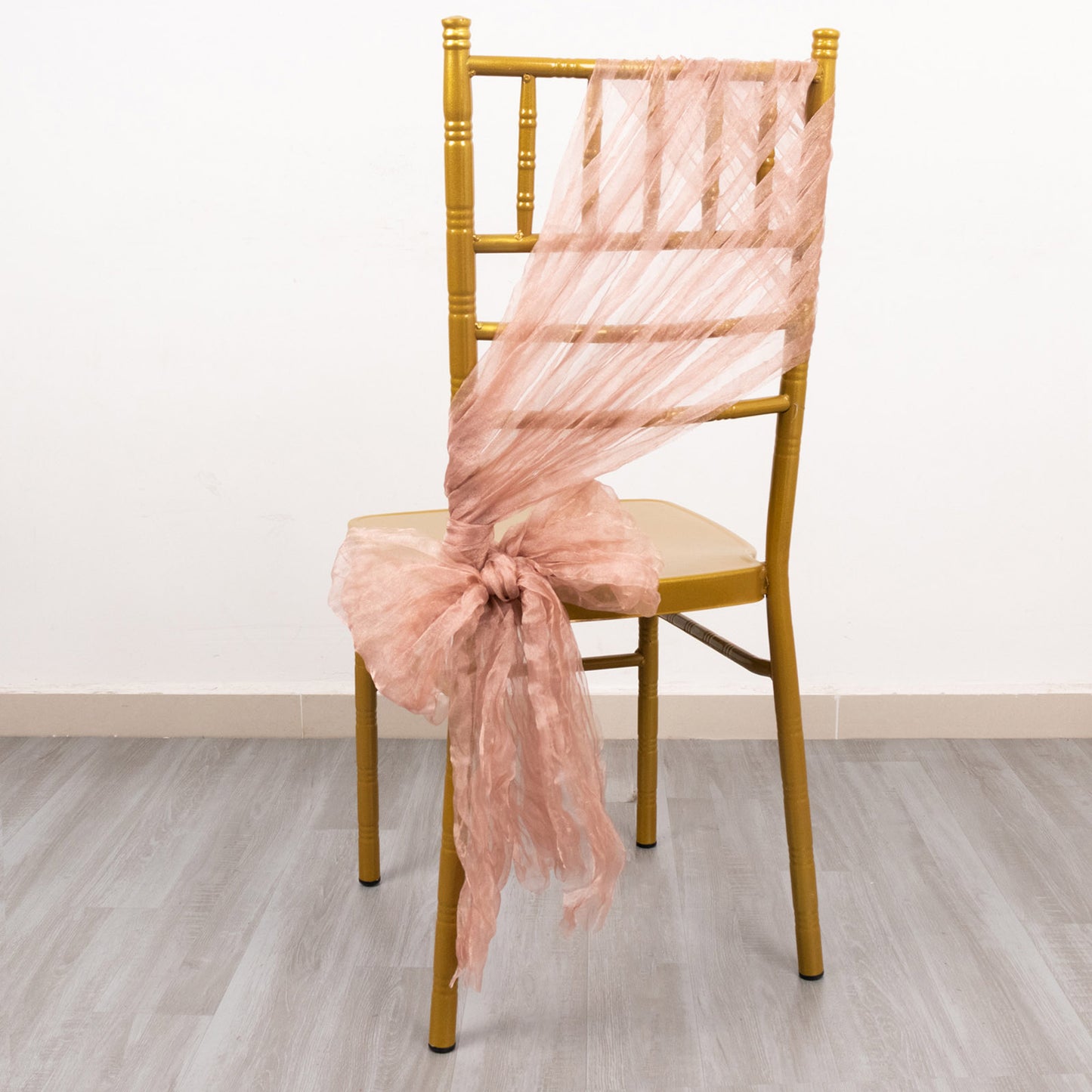 Dusty rose sheer crinkled organza chair sash on a gold chair.