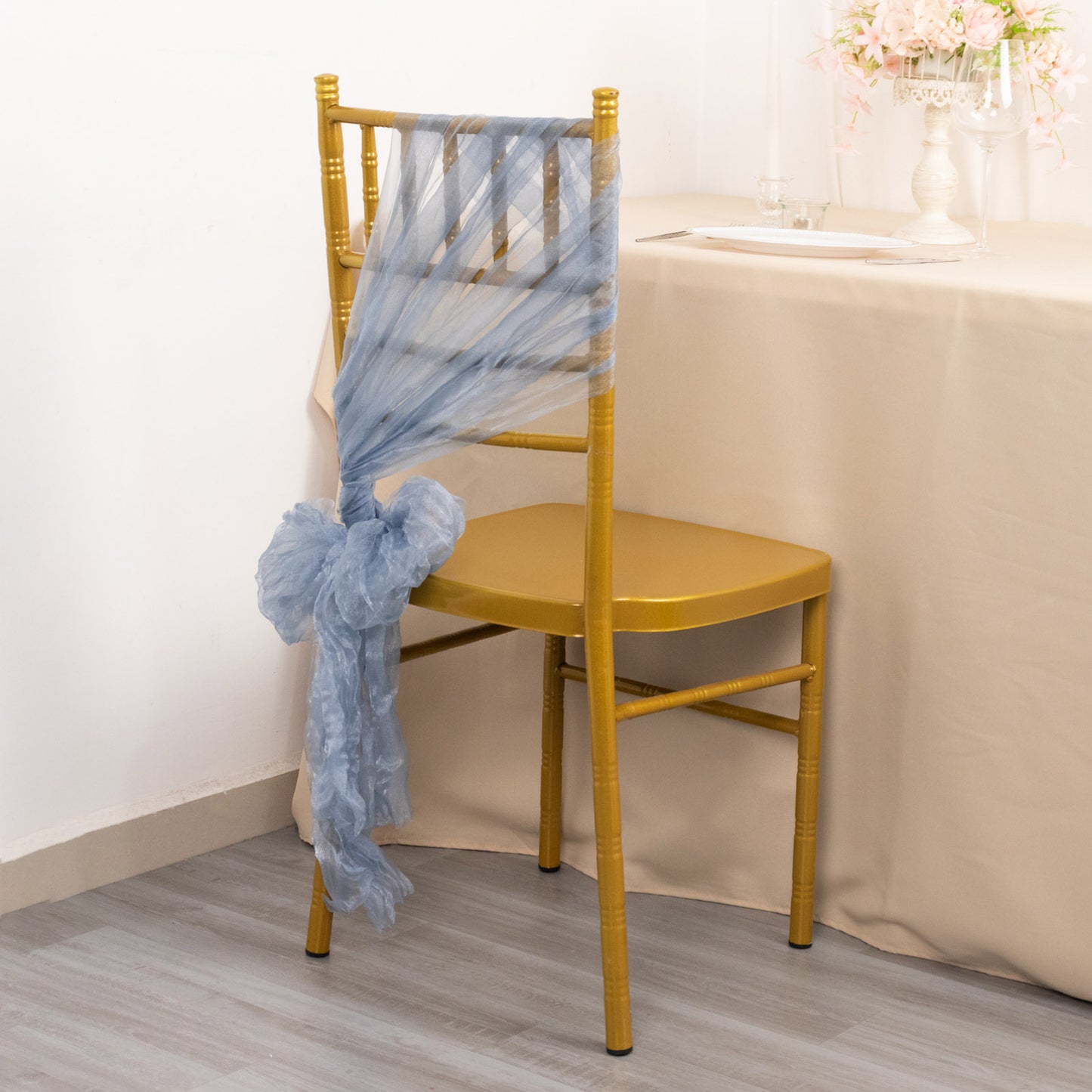 Dusty blue sheer crinkled organza chair sash on a gold chair.