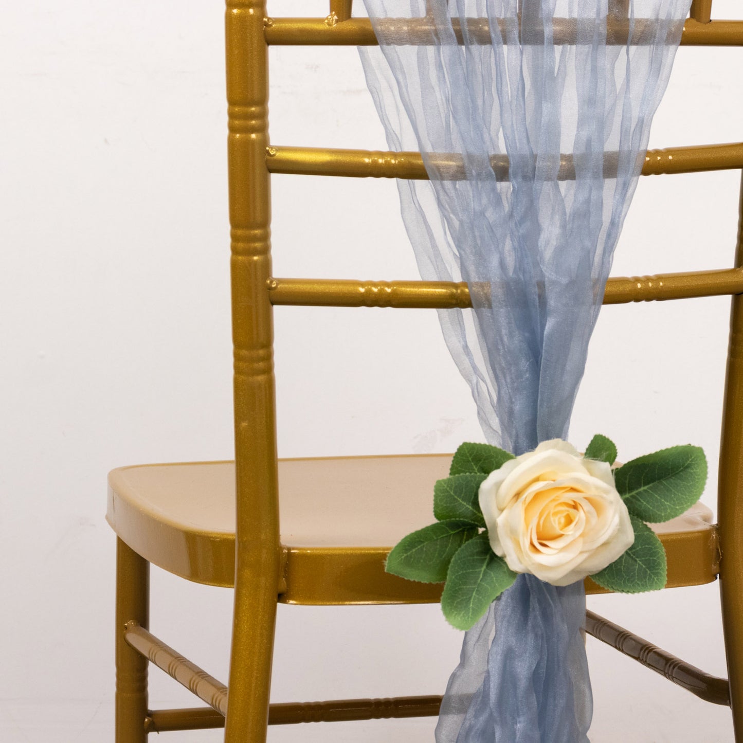Dusty blue sheer crinkled organza chair sash on a gold chair.