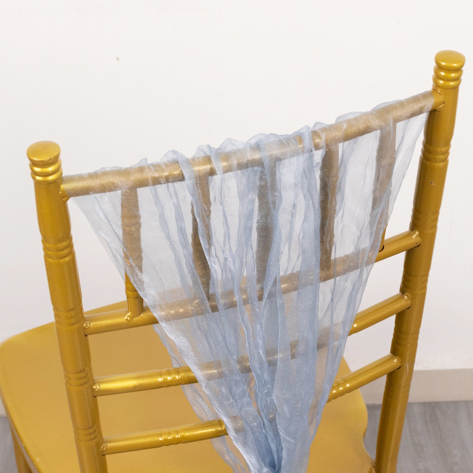 Dusty blue sheer crinkled organza chair sash on a gold chair.