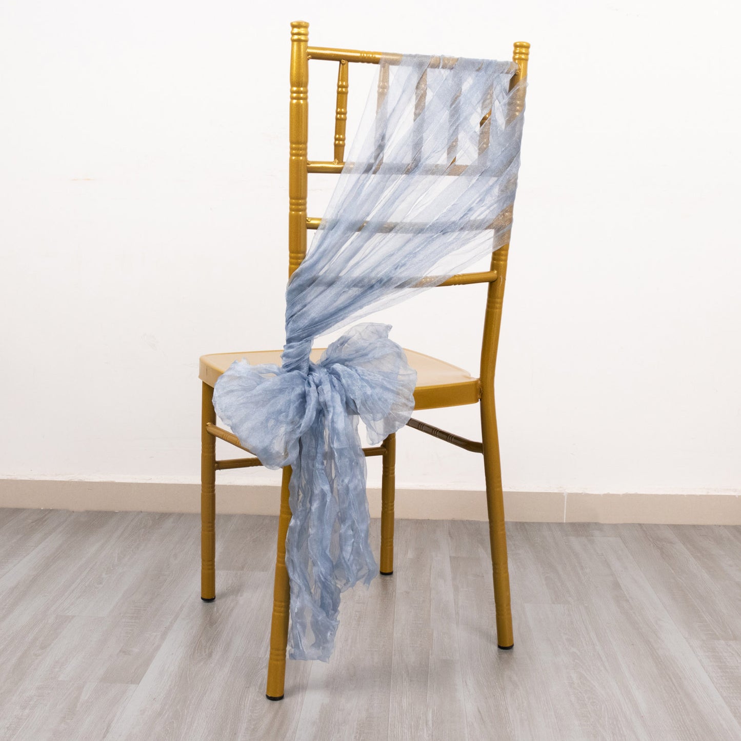 Dusty blue sheer crinkled organza chair sash on a gold chair.