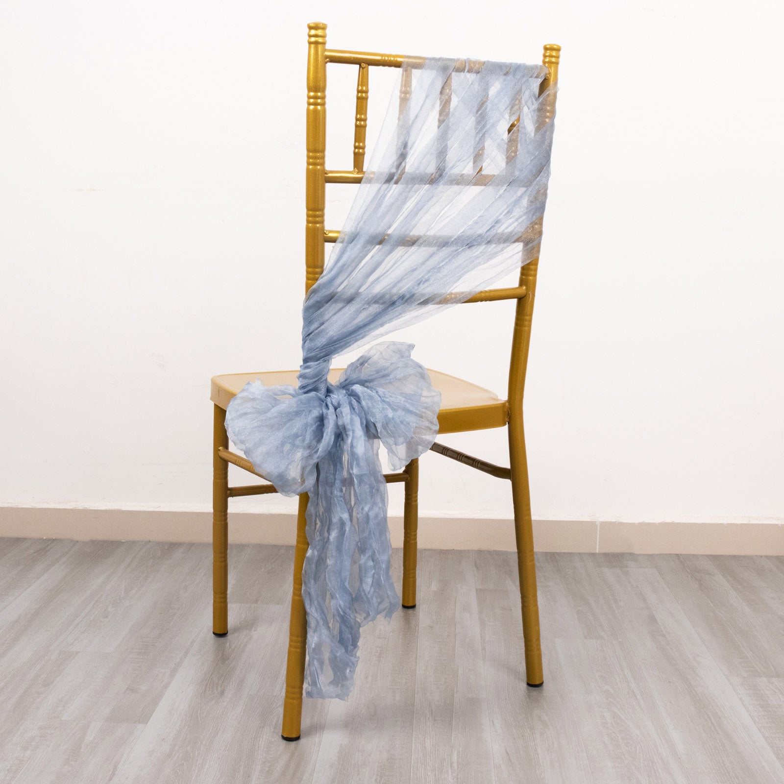Dusty blue sheer crinkled organza chair sash on a gold chair.