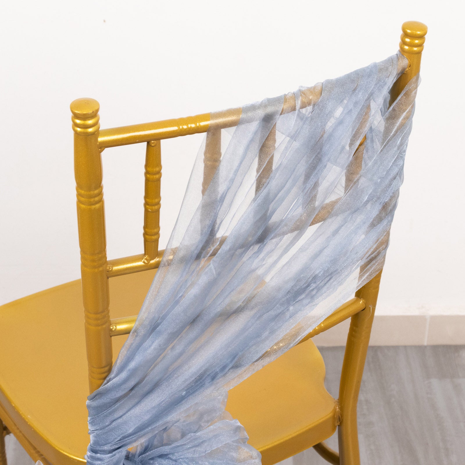 Dusty blue sheer crinkled organza chair sash on a gold chair.