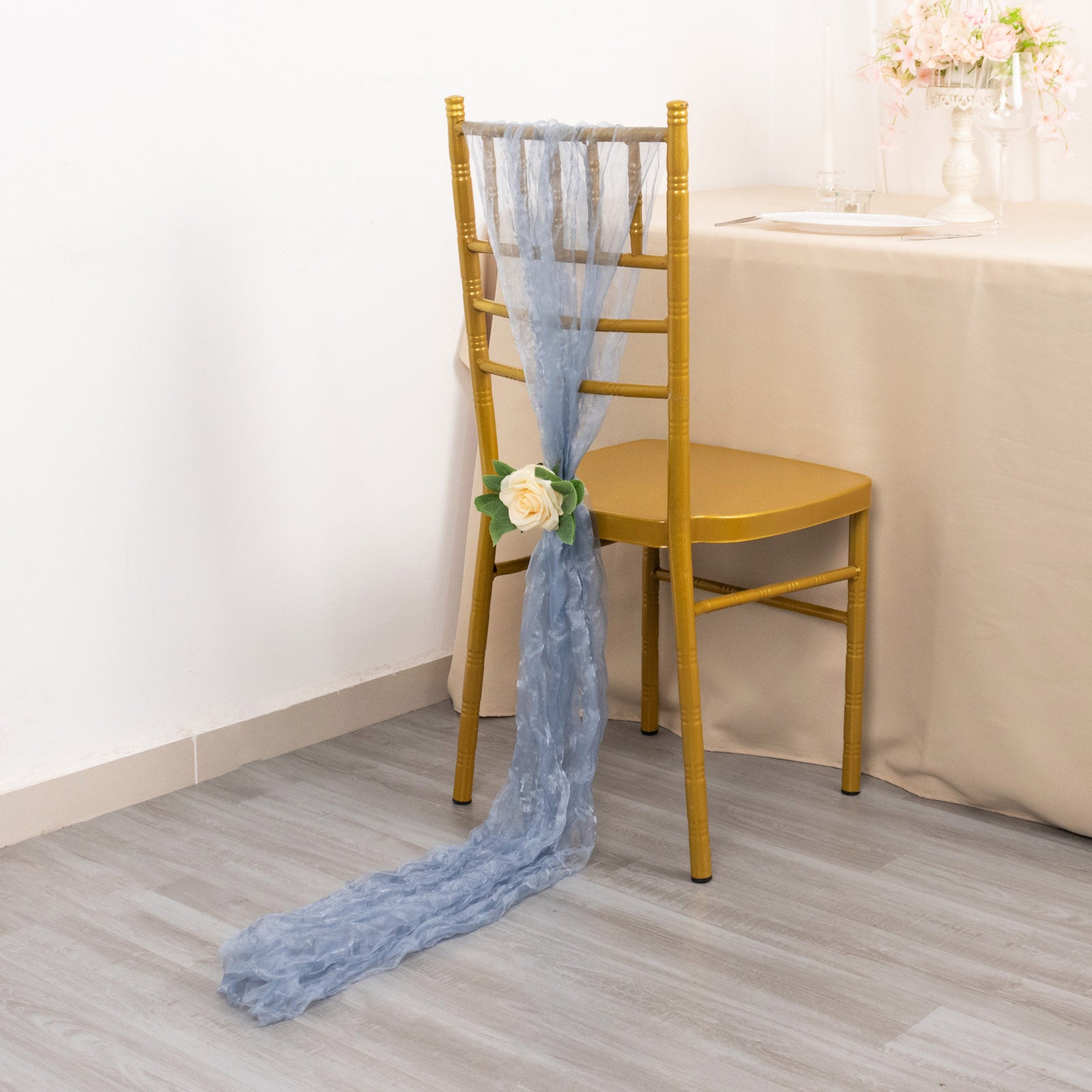 Dusty blue sheer crinkled organza chair sash tied on a gold chair.