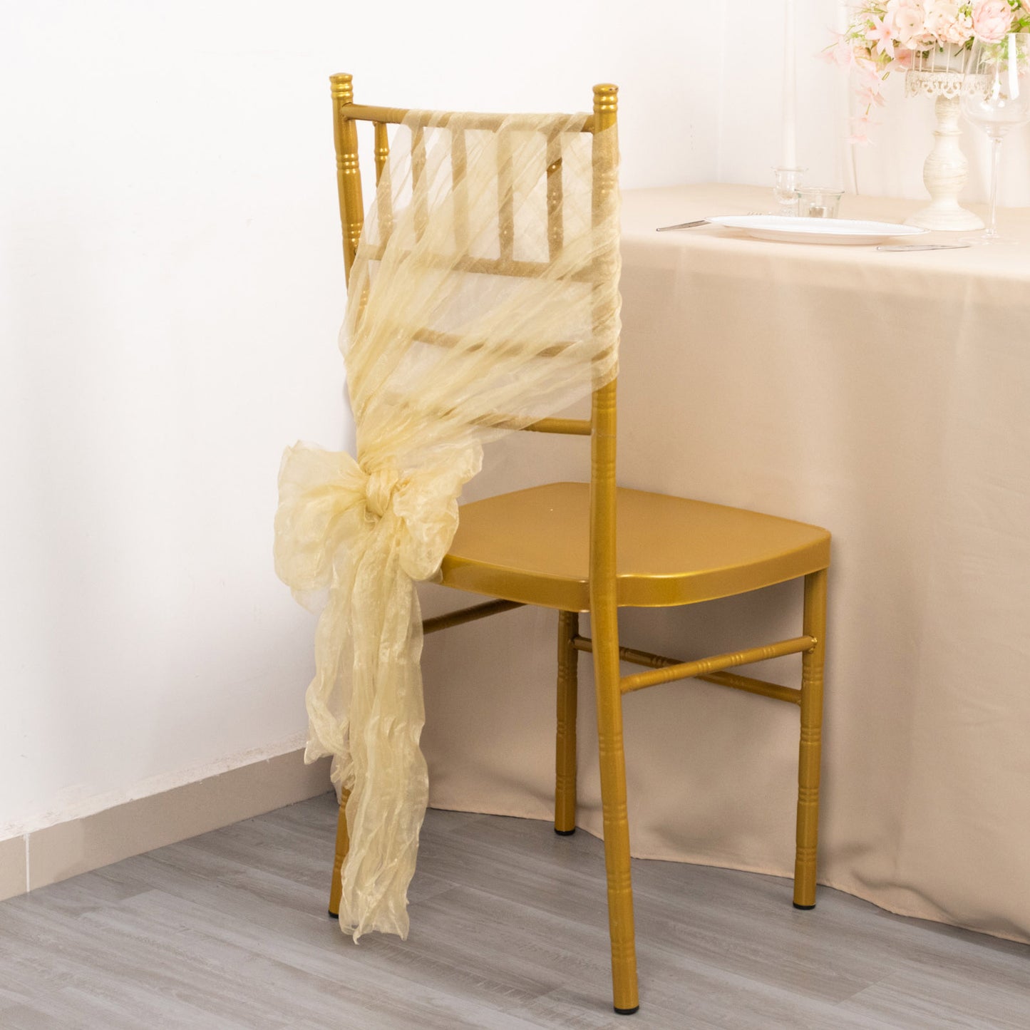 Champagne sheer crinkled organza chair sash on a gold chair.