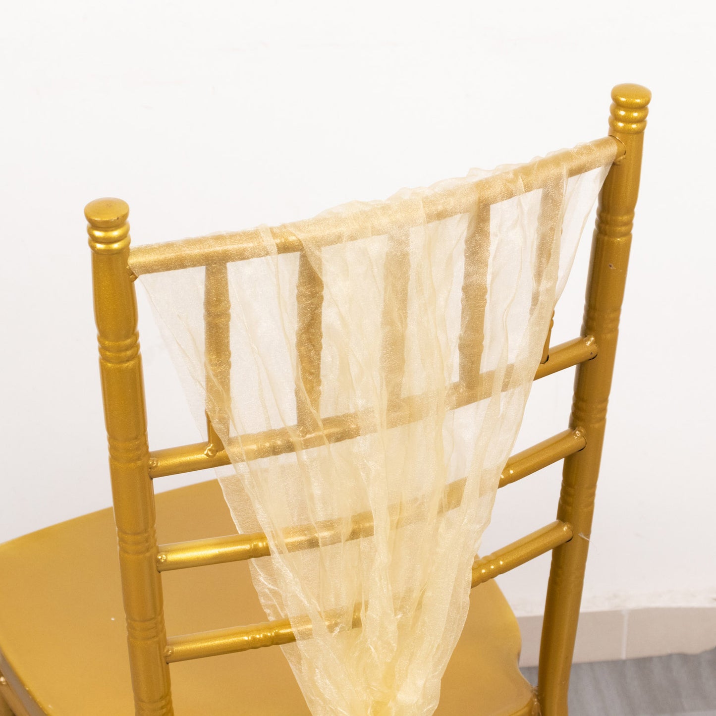 Champagne sheer crinkled organza chair sash on a gold chair.