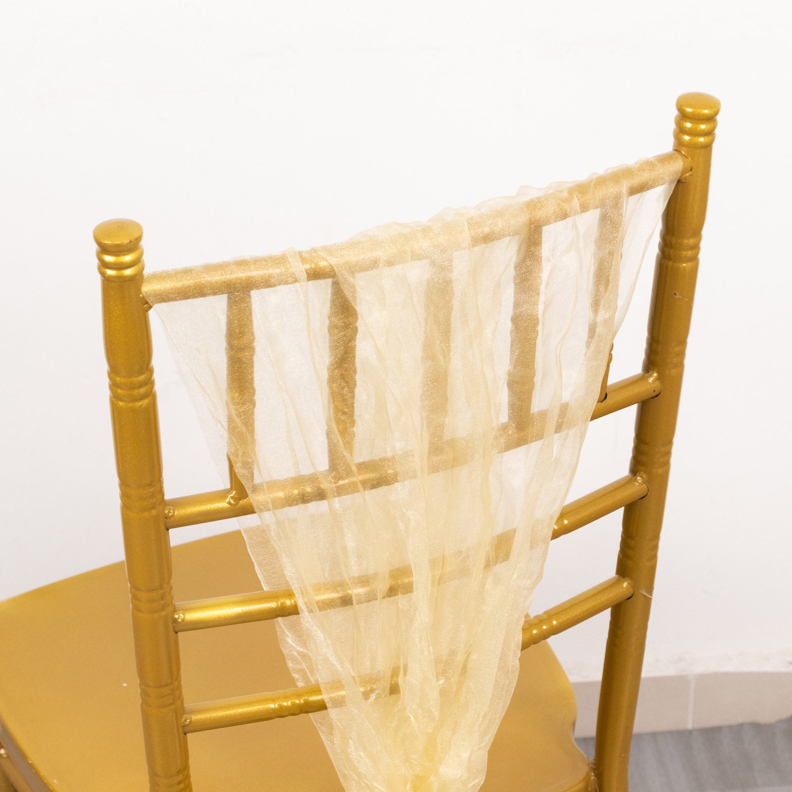 Champagne sheer crinkled organza chair sash on a gold chair.