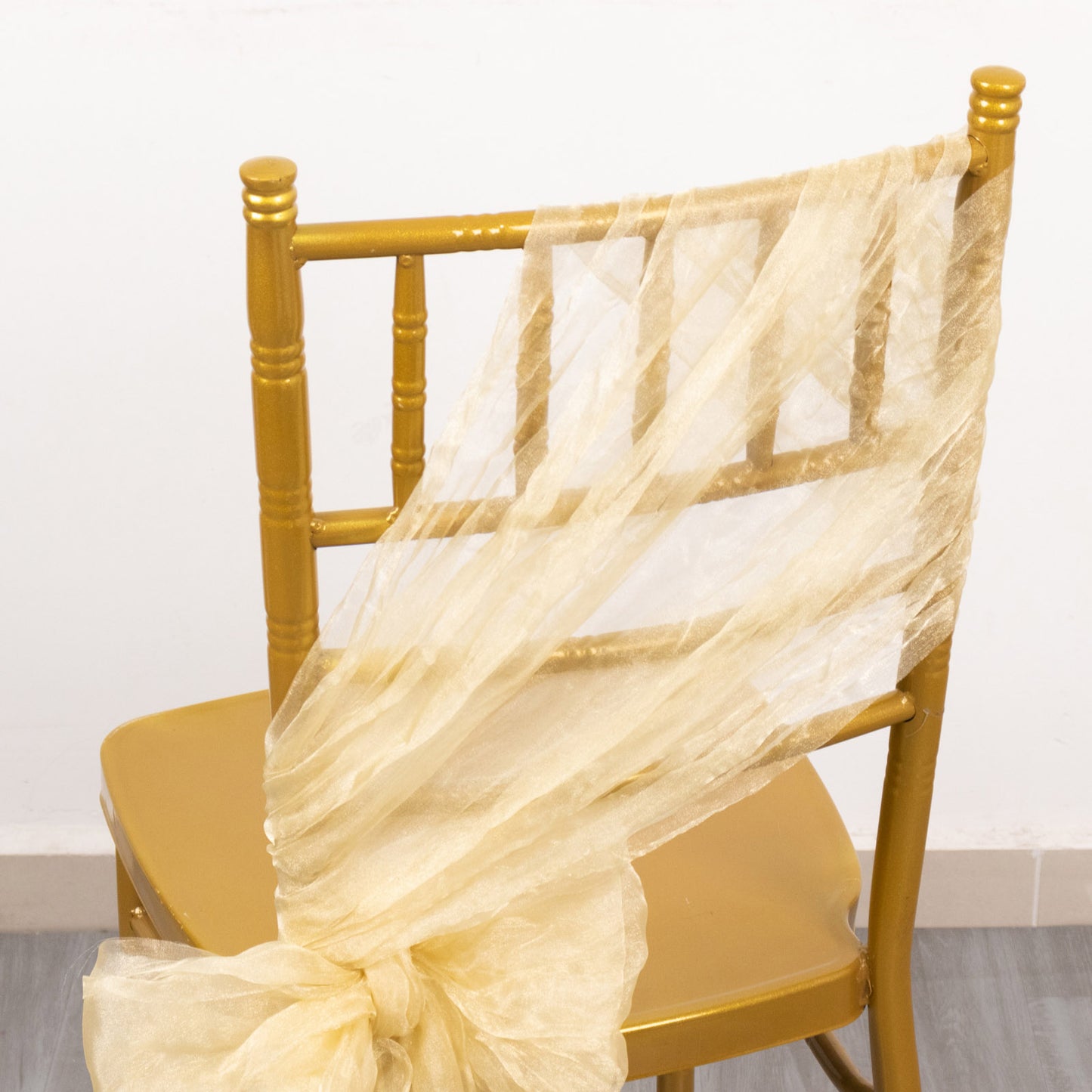 Champagne sheer crinkled organza chair sash on a gold chair.
