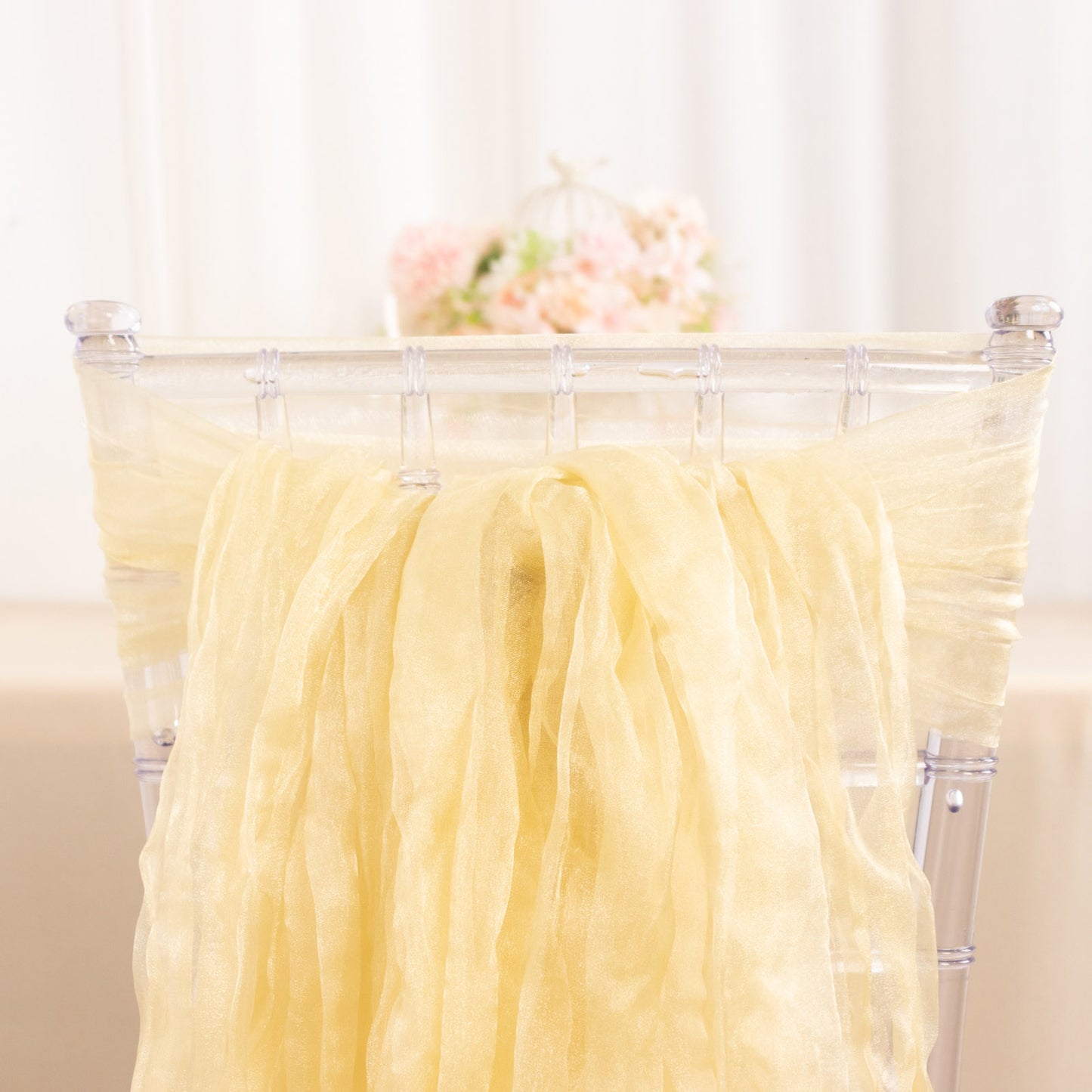 Champagne sheer crinkled organza chair sashes on a transparent chair.