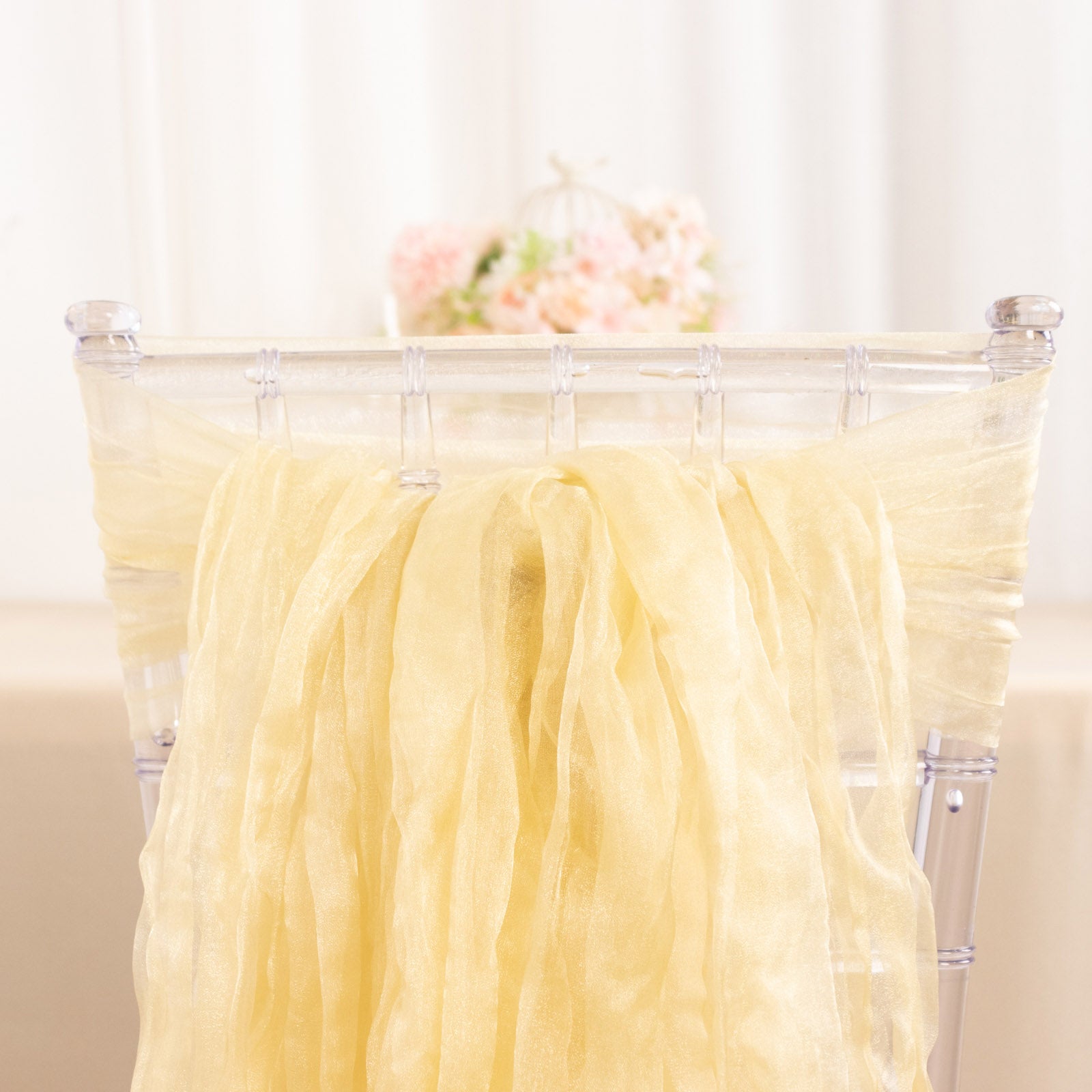 Champagne sheer crinkled organza chair sashes on a transparent chair.