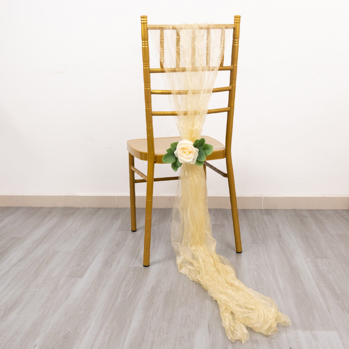 Champagne sheer crinkled organza chair sash draped on a gold chair.