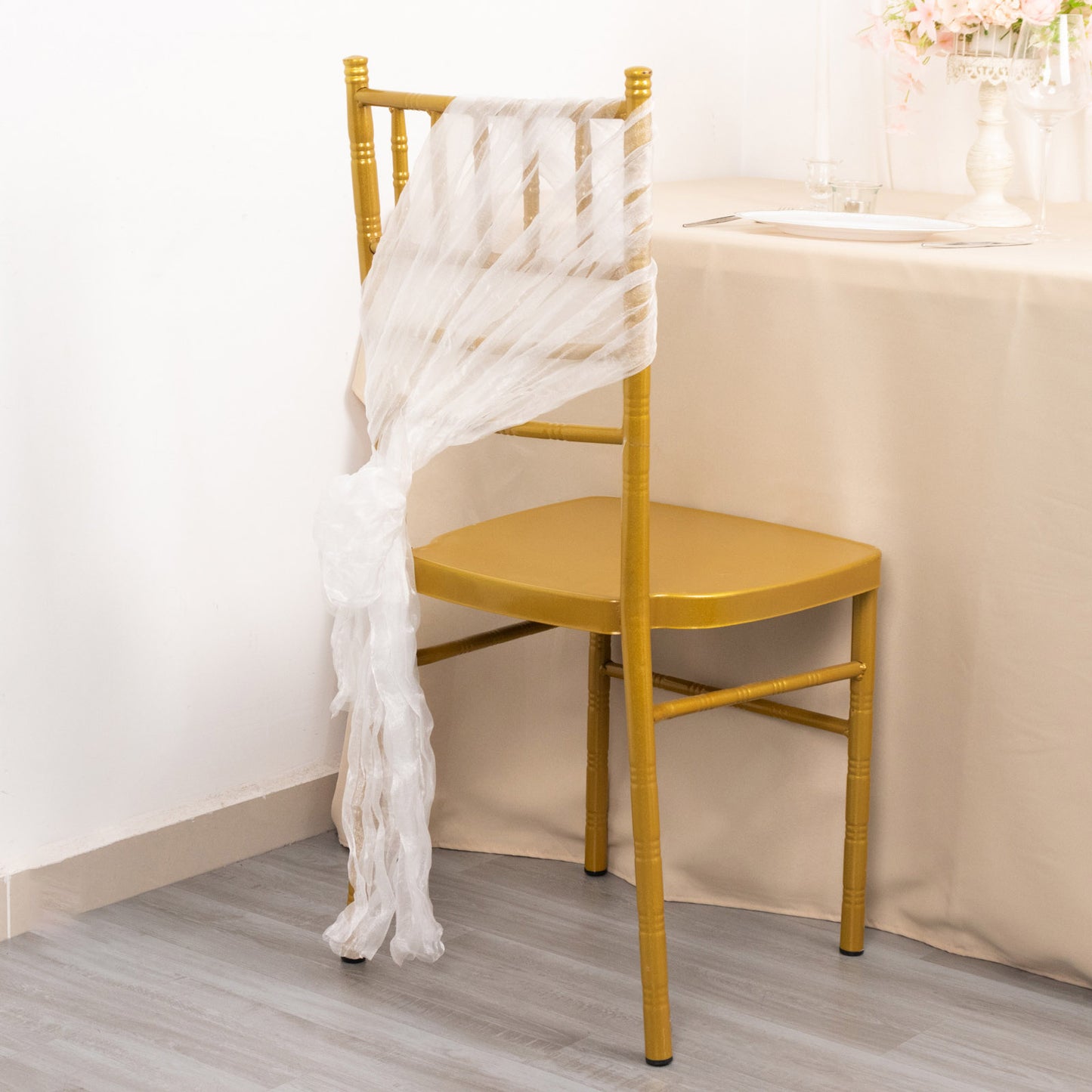 White sheer crinkled organza chair sash on a gold chair.