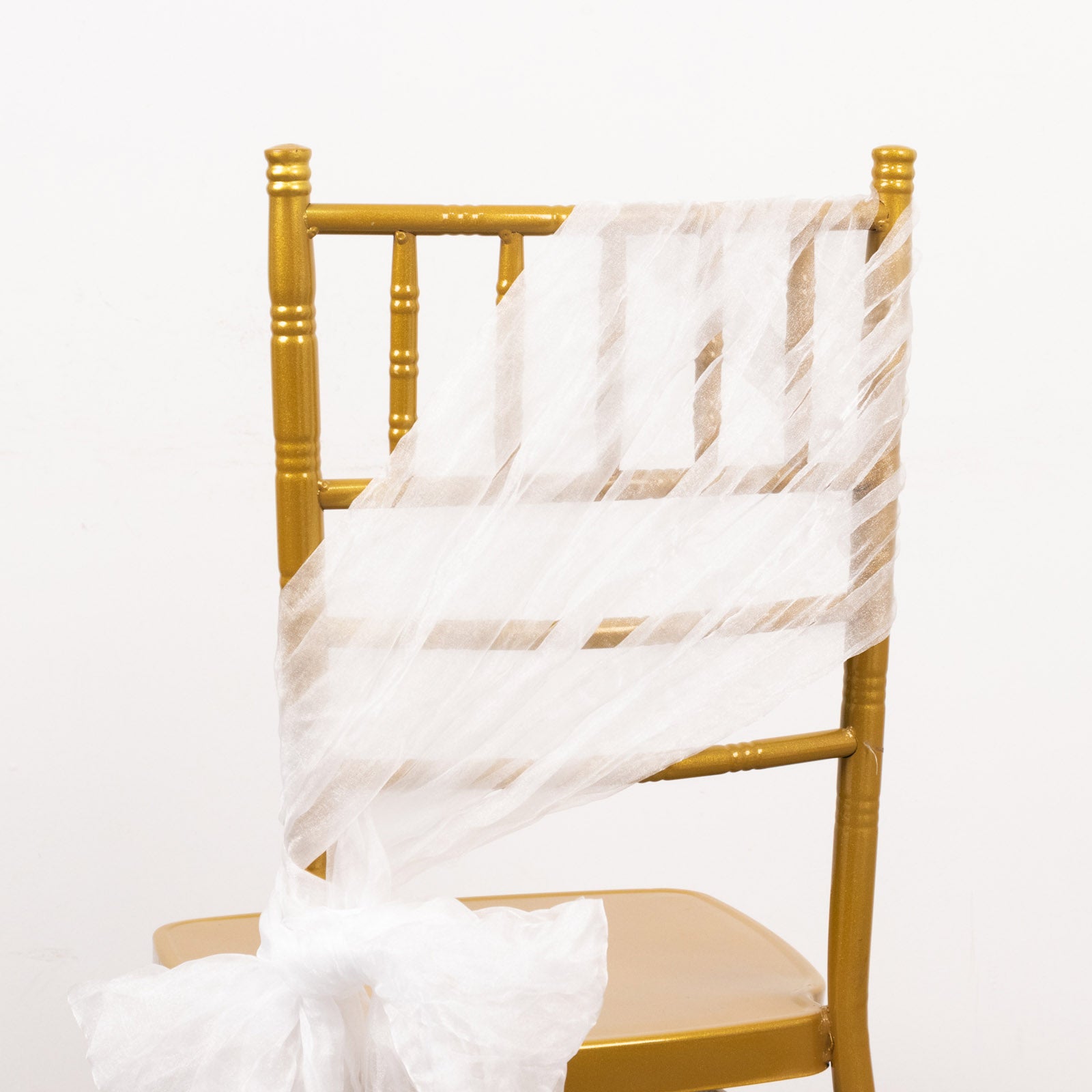 White sheer crinkled organza chair sash on a gold chair.