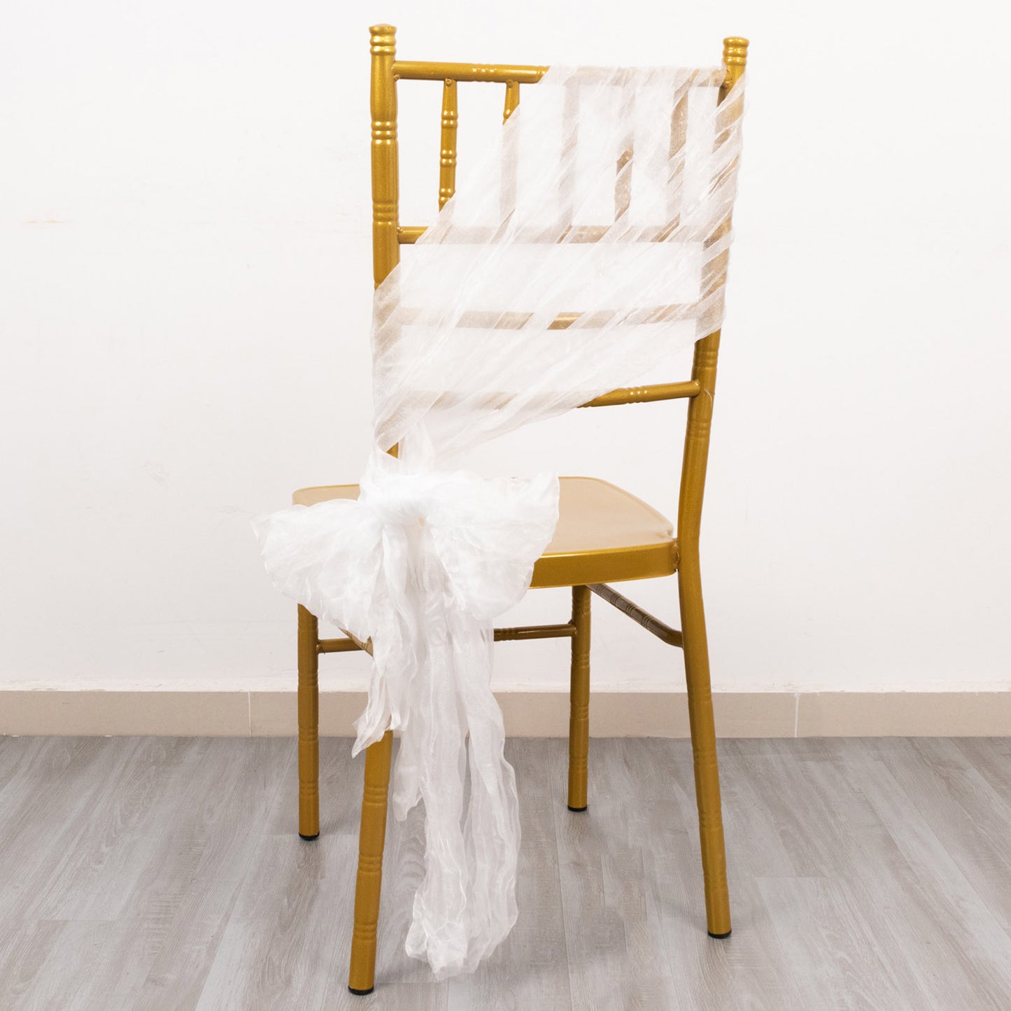 White sheer crinkled organza chair sash on a gold chair.
