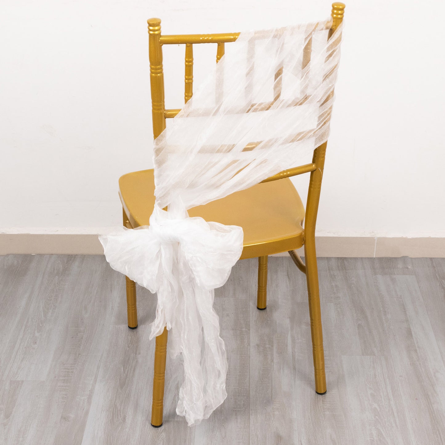 White sheer crinkled organza chair sash on a gold chair.