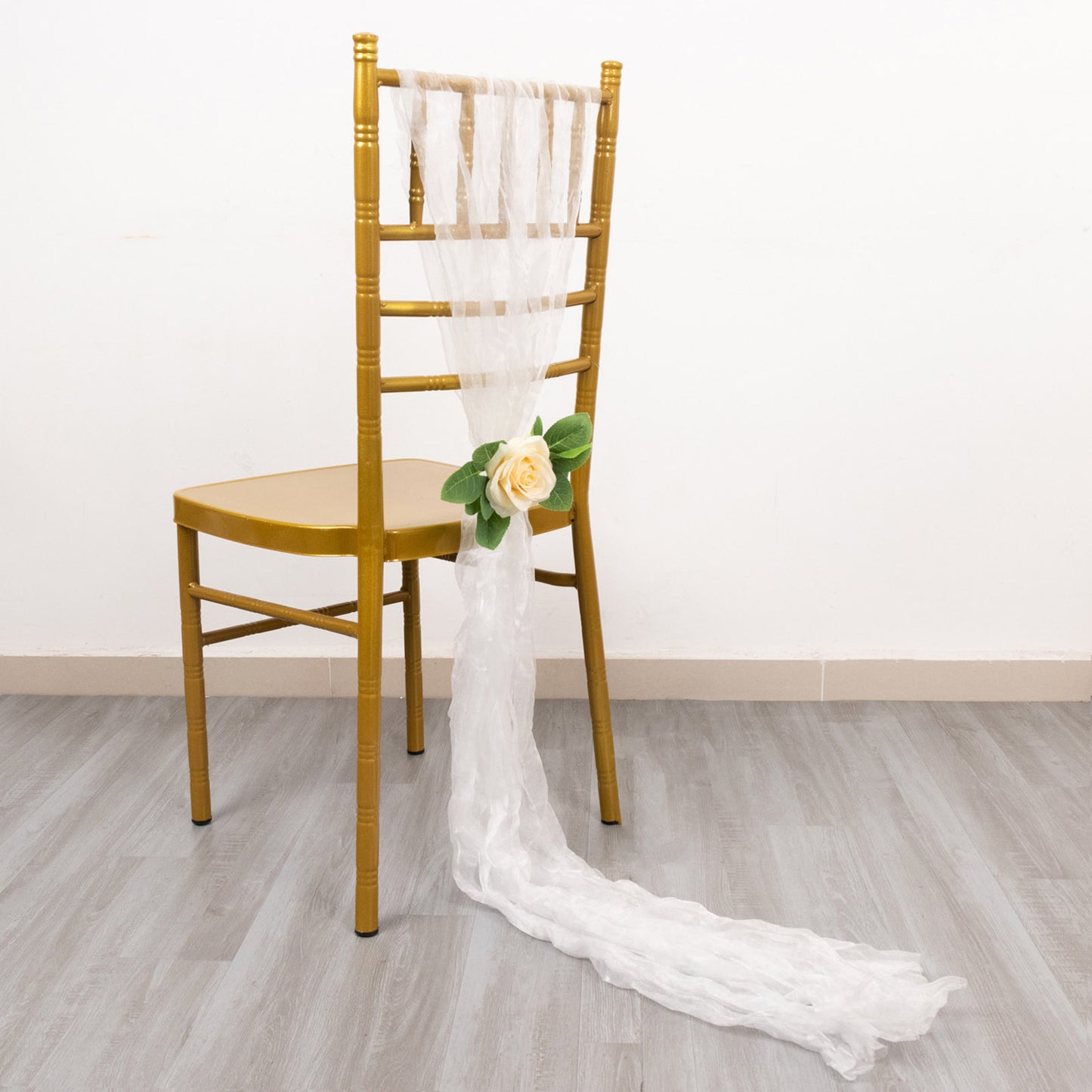 White sheer crinkled organza chair sashes on a gold chair.