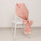 Dusty rose satin chair sash tied in a bow on a white chair.