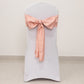Dusty rose satin chair sash tied in a bow on a white chair.