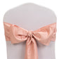 Dusty rose satin chair sash tied in a bow on a white chair.