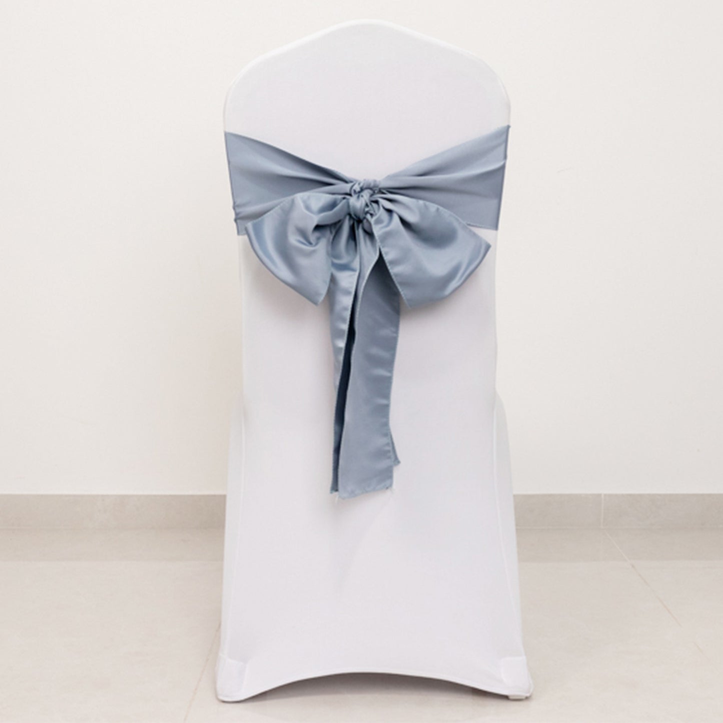 Dusty blue satin chair sash bow on a white chair.