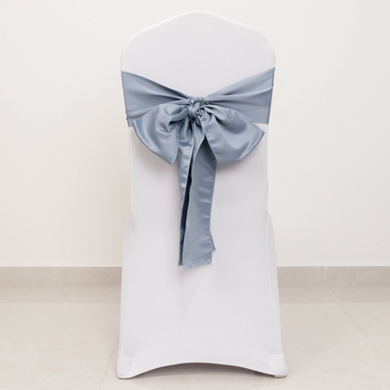 Dusty blue satin chair sash bow on a white chair.