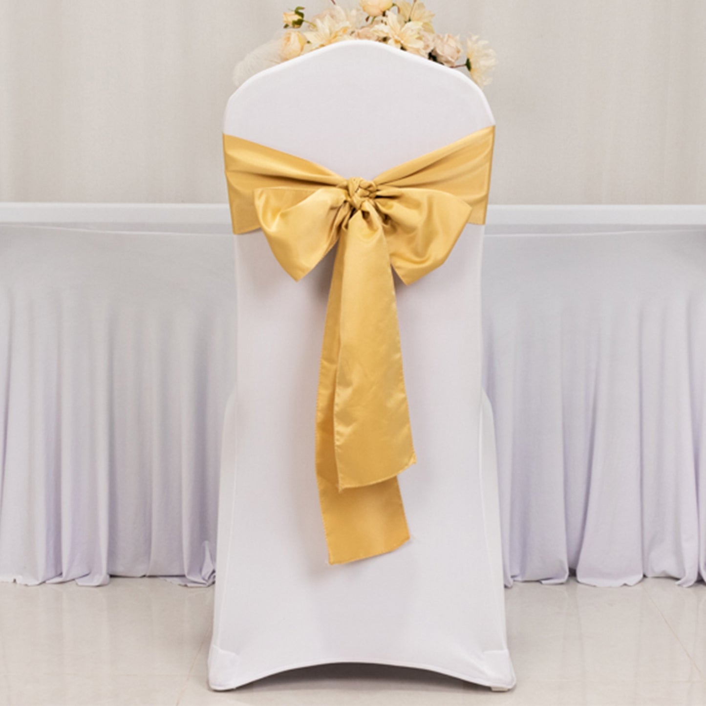Champagne satin chair sash bow on a white chair.