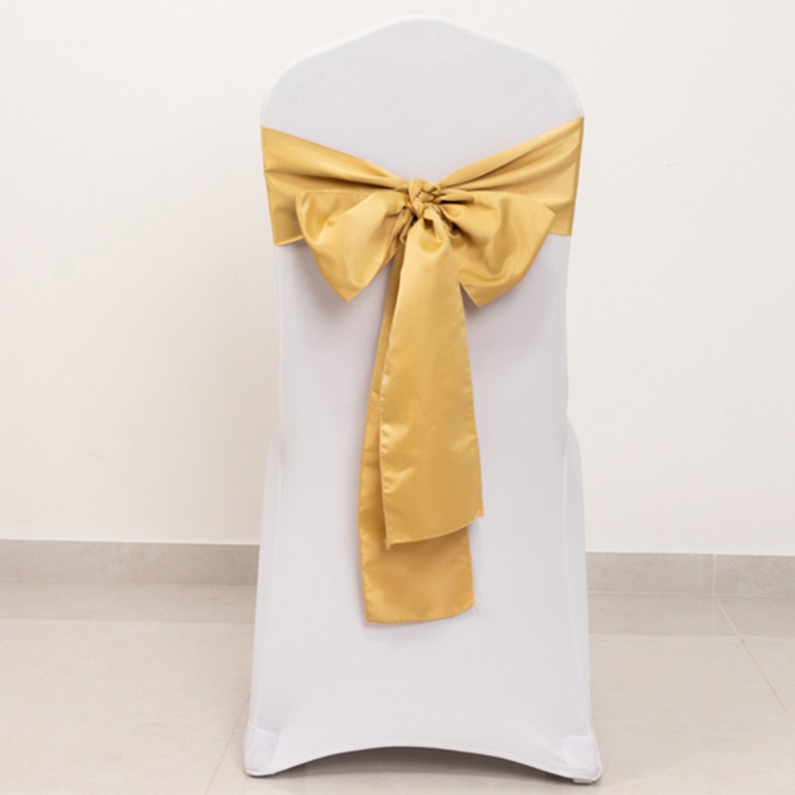 Champagne satin chair sash bow on a white chair.