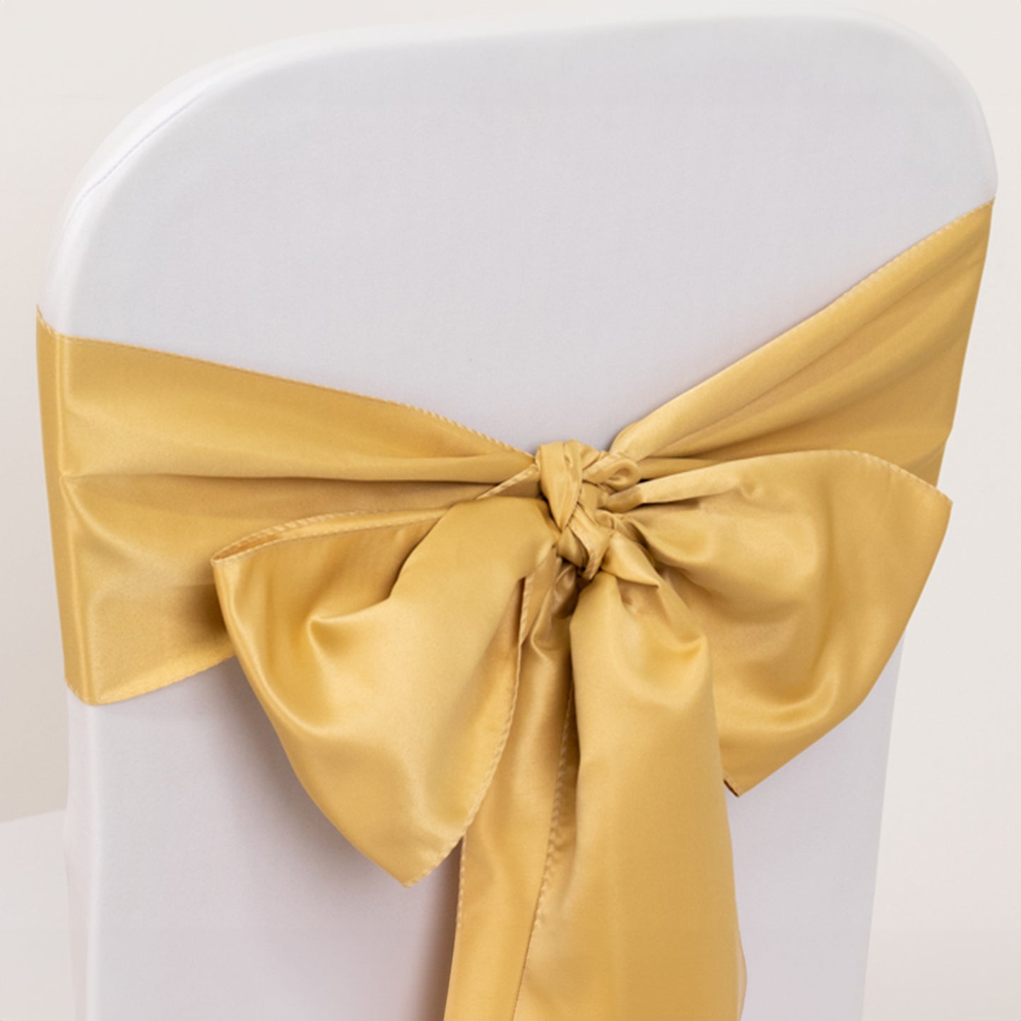 Champagne satin chair sash bow on a white chair.