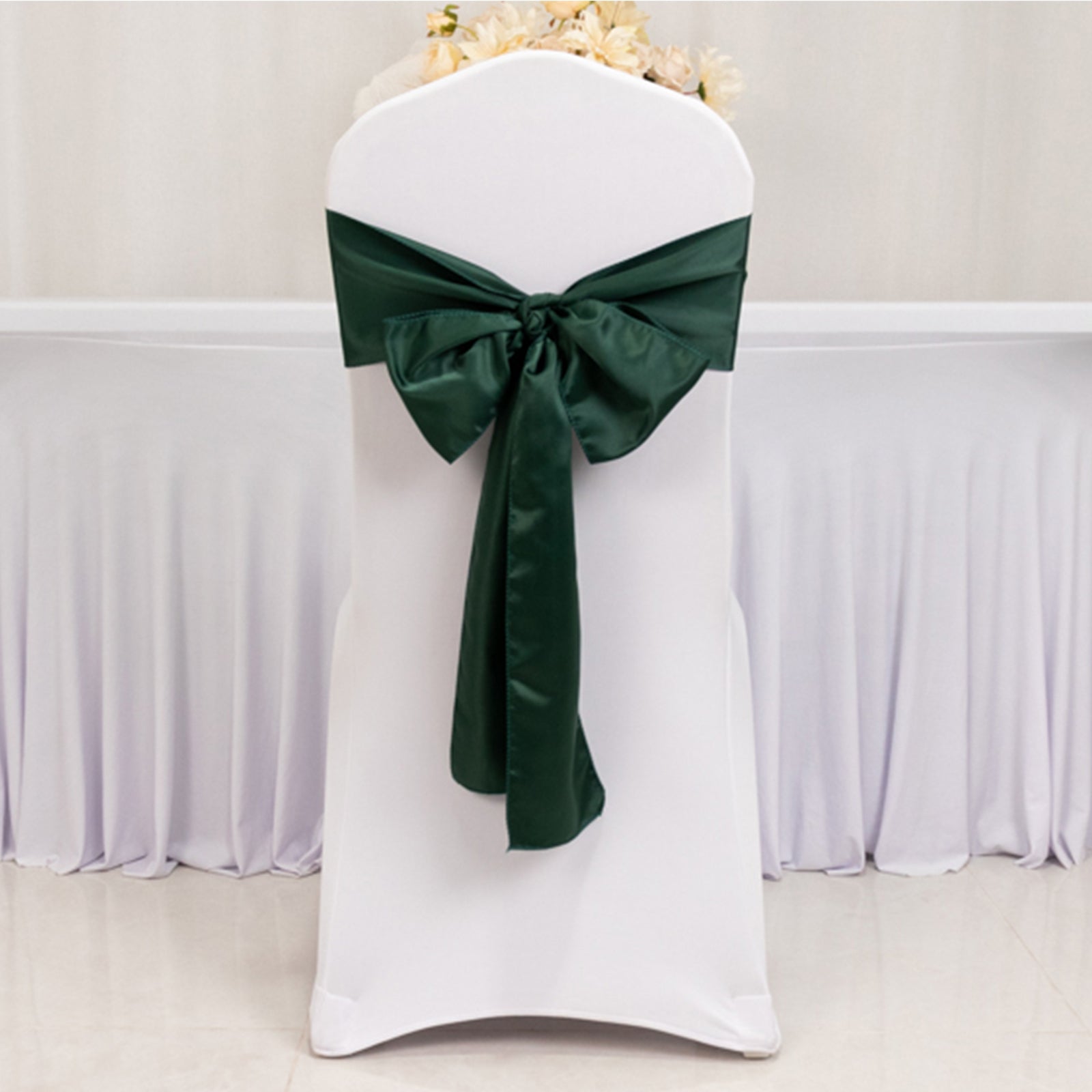 Emerald green satin chair sash bow on a white chair.