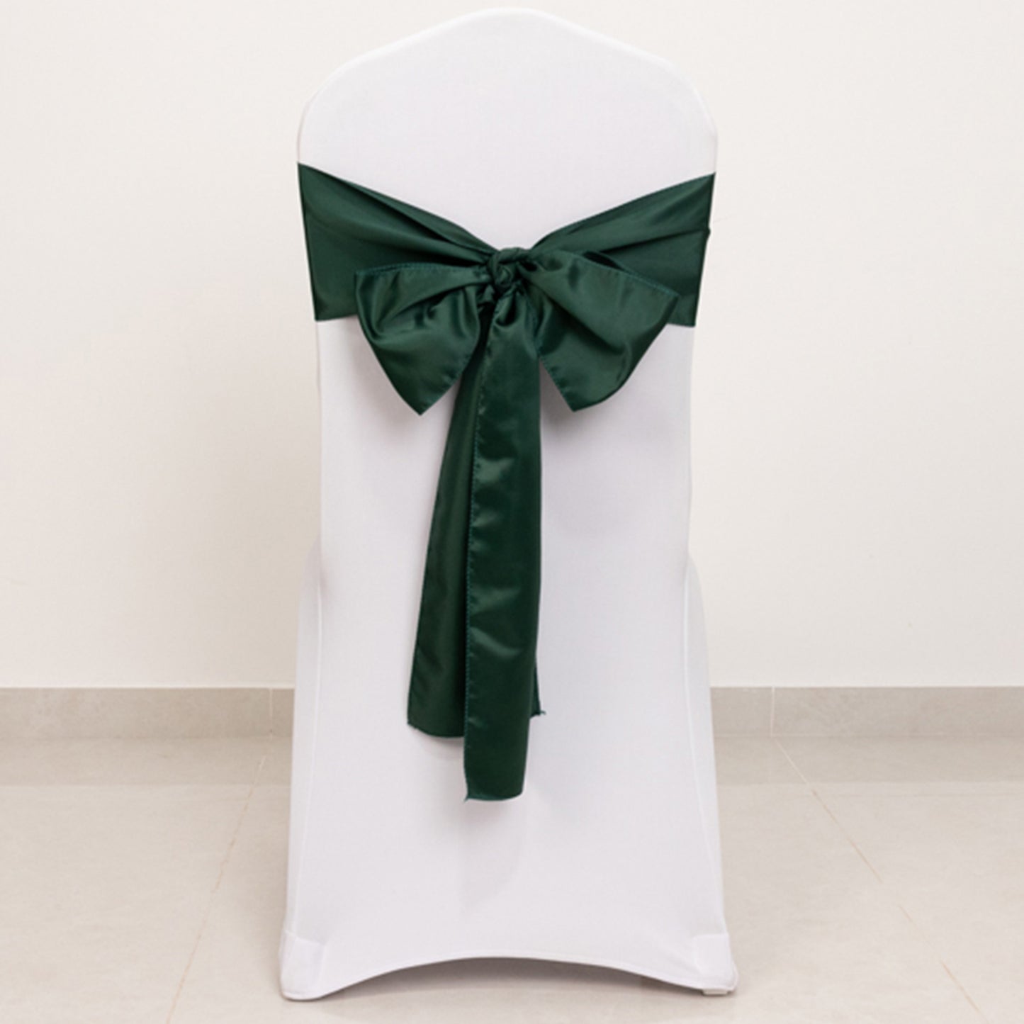 Emerald green satin chair sash bow on a white chair.