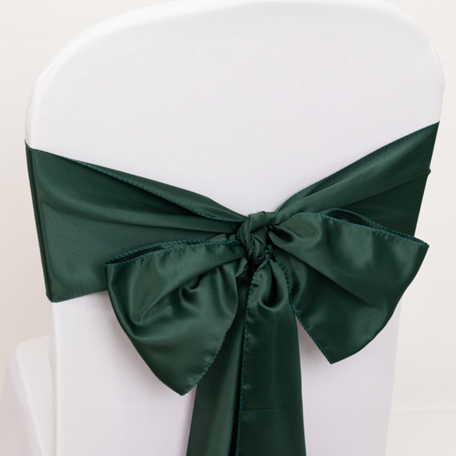 Hunter emerald green satin chair sash tied in a bow on a white chair.