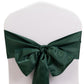 Emerald green satin chair sash tied in a bow on a white chair.