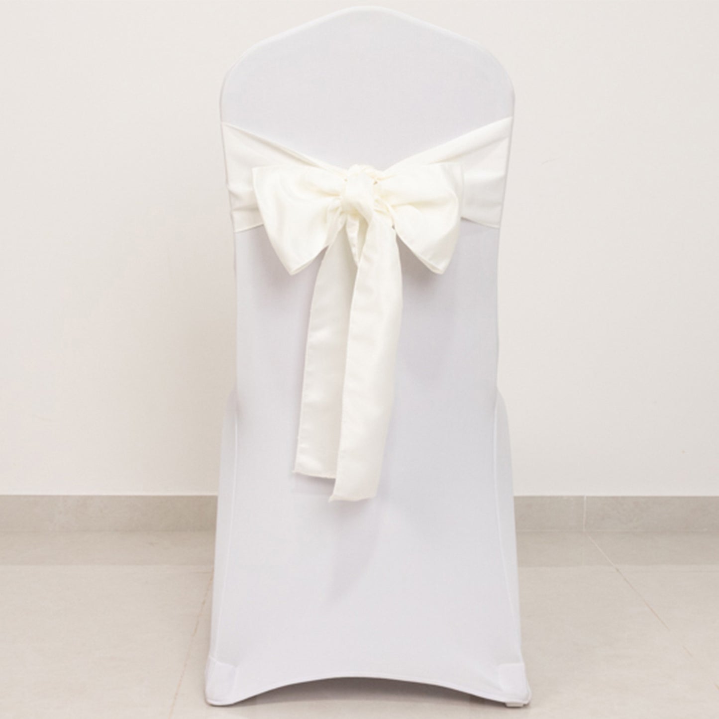 Ivory satin chair sash bow on a white chair.