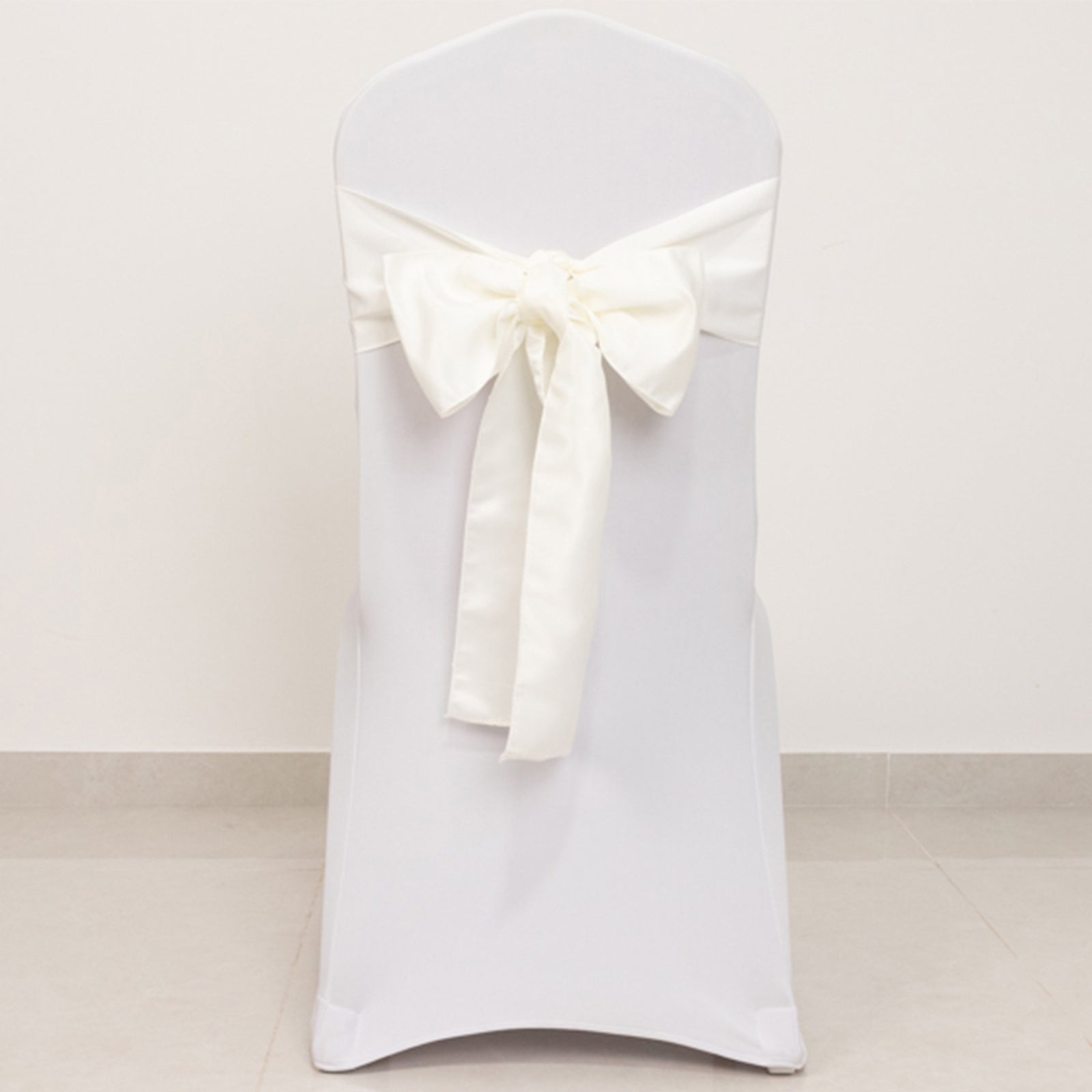 Ivory satin chair sash bow on a white chair.