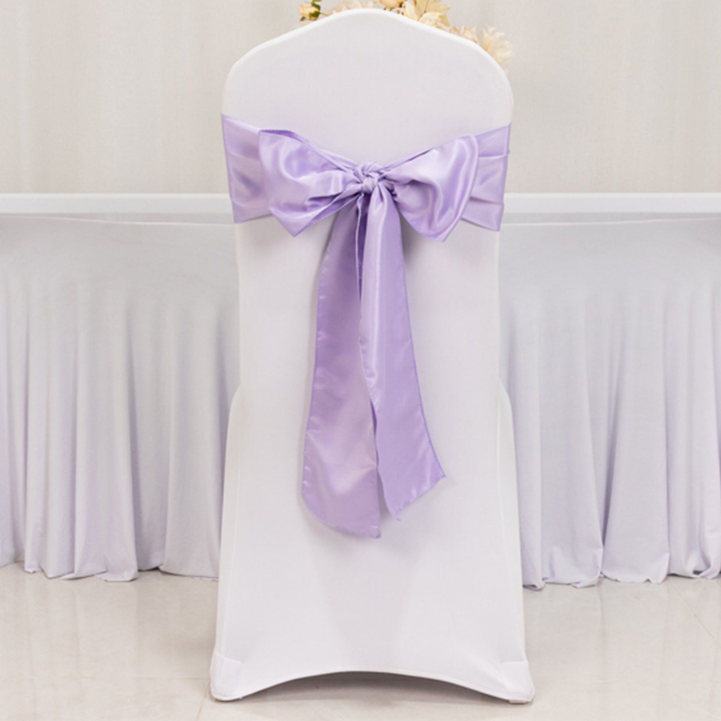 Lavender satin chair sash bow on a white chair.