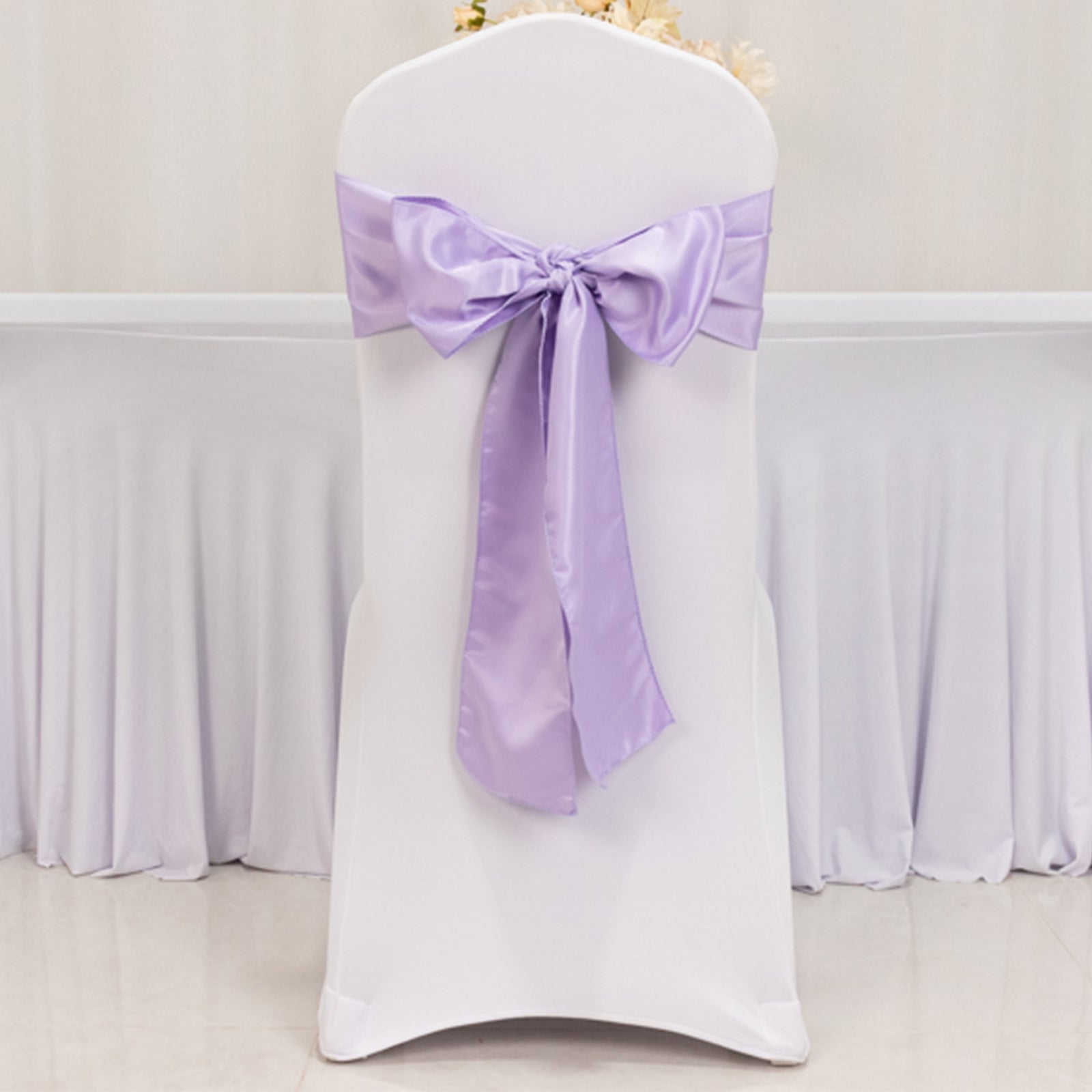 Lavender satin chair sash bow on a white chair.