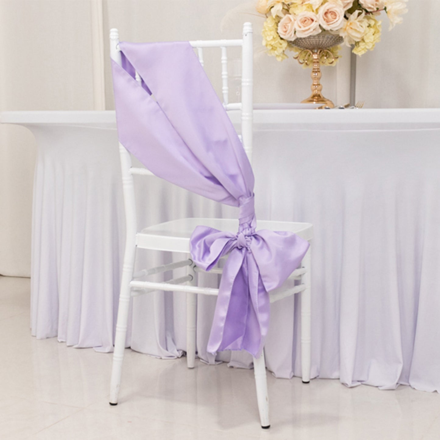 Lavender satin chair sash tied in a bow on a white chair.