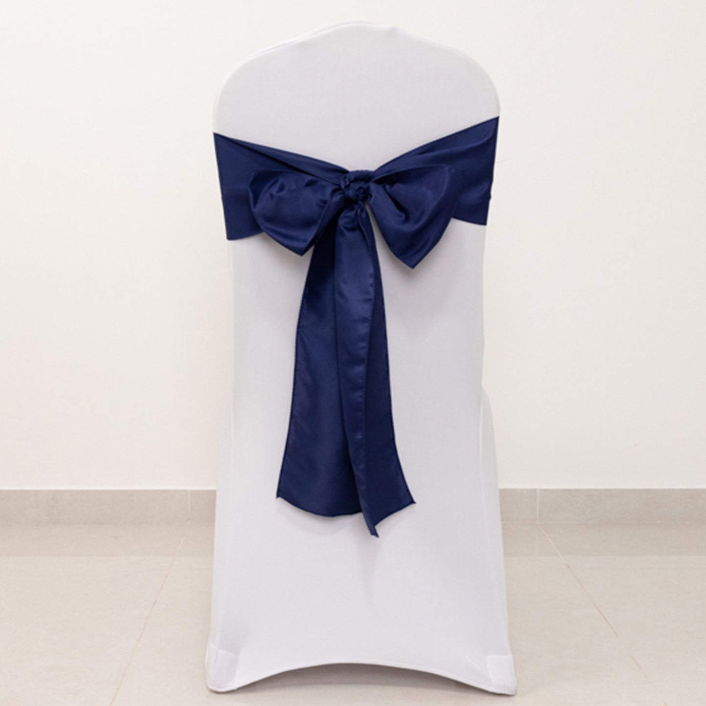 Navy blue satin chair sash with bow on a white chair