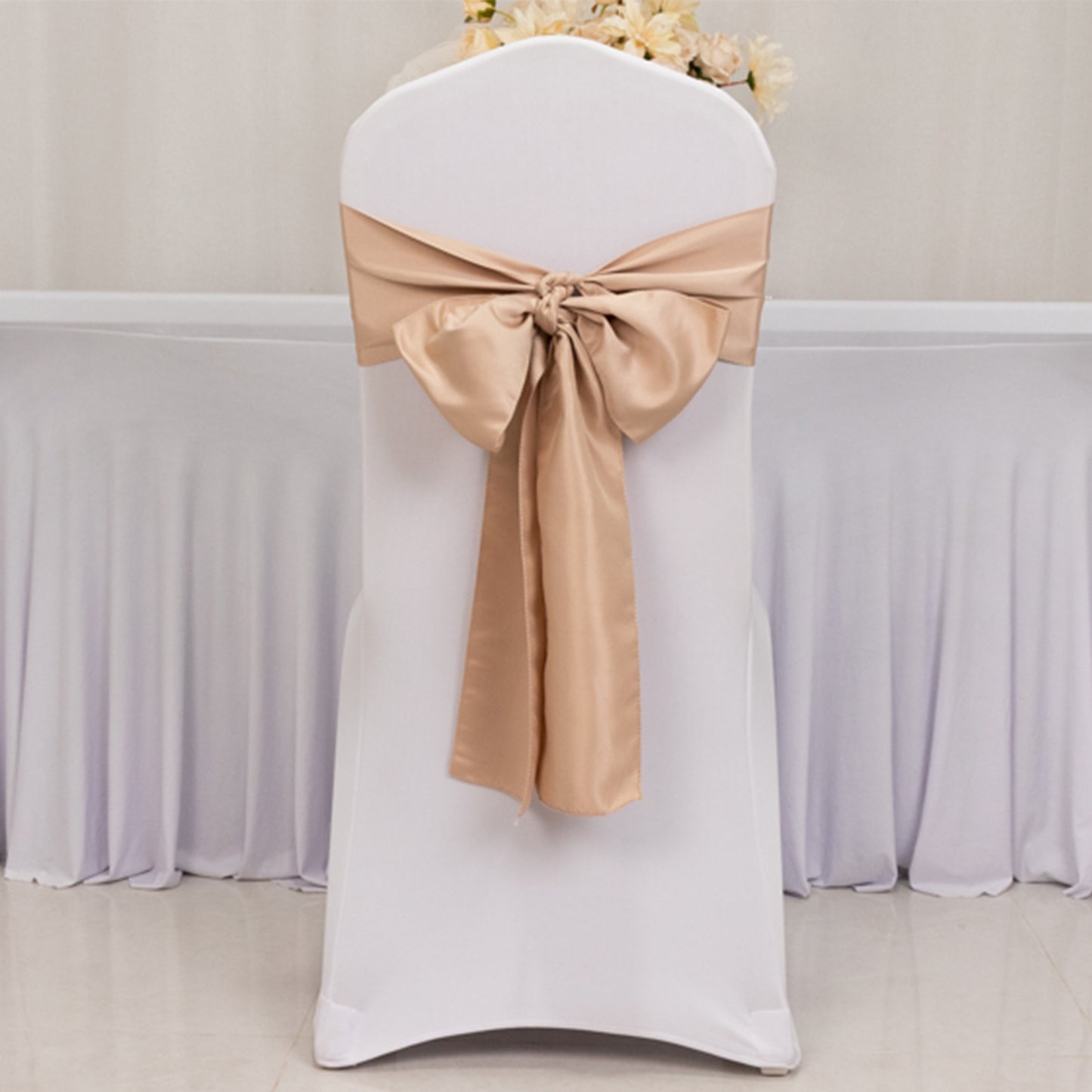 Nude satin chair sash bow on a white chair for elegant decor.