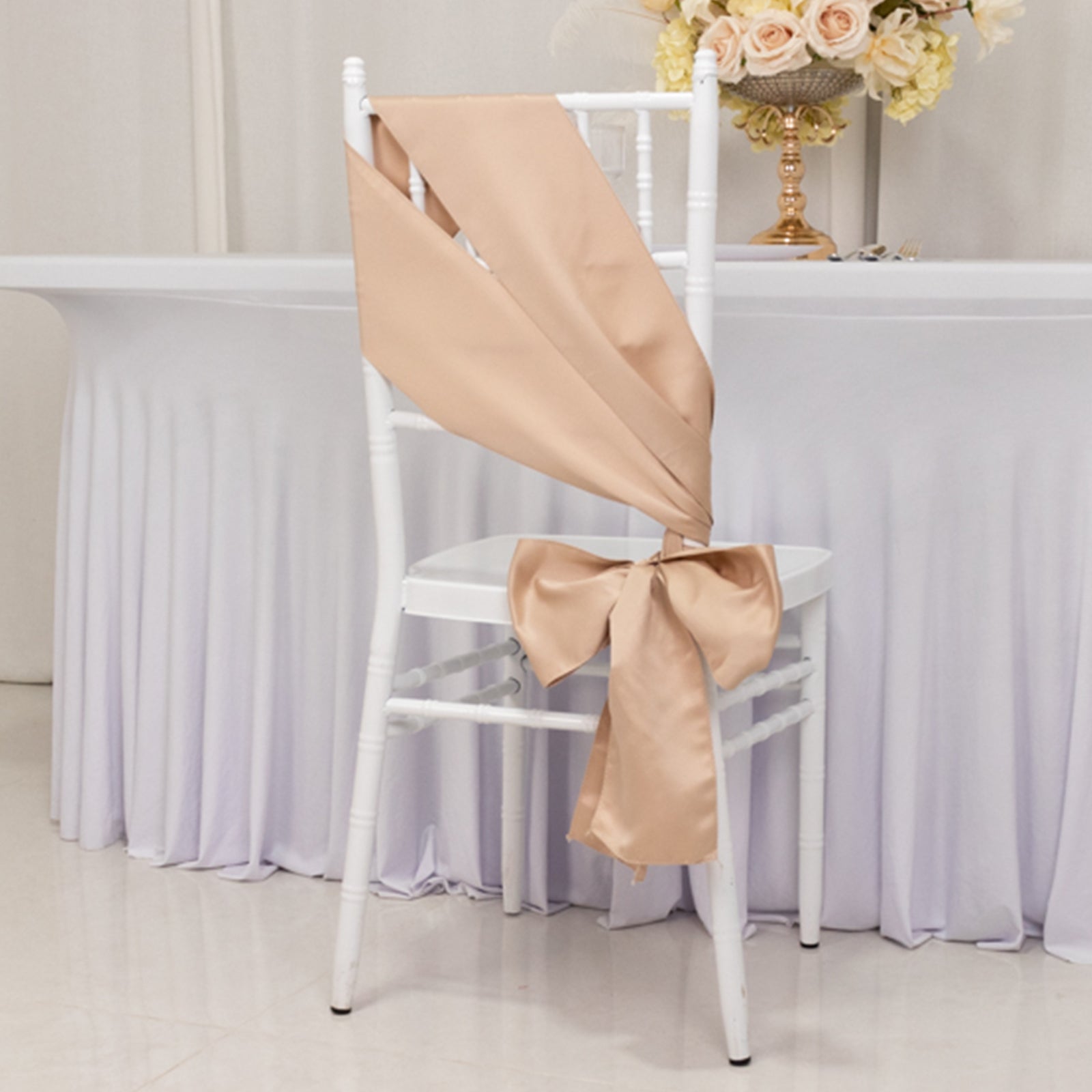 Nude satin chair sashes and bows on a white chair.
