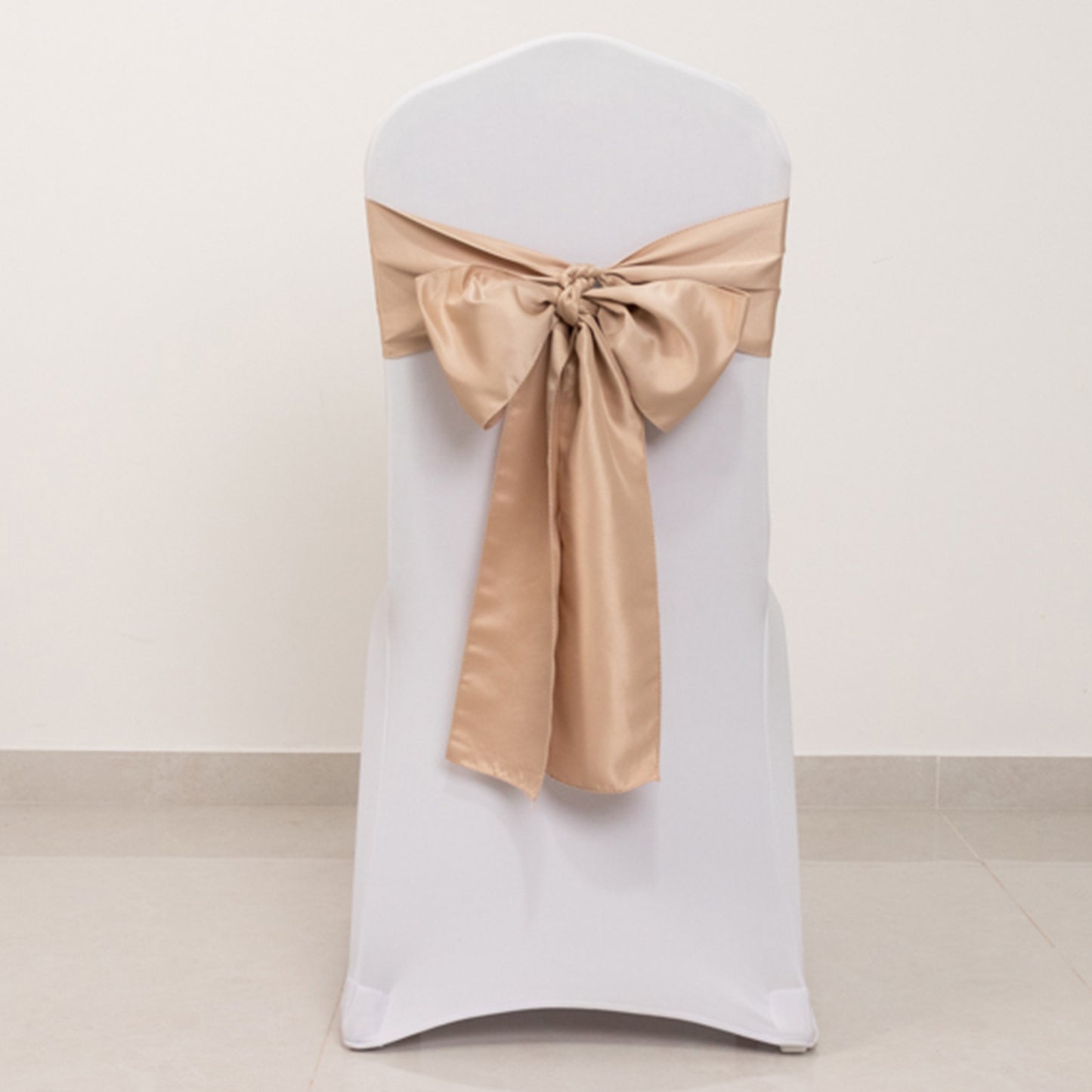 Nude satin chair sash bow on a white chair.