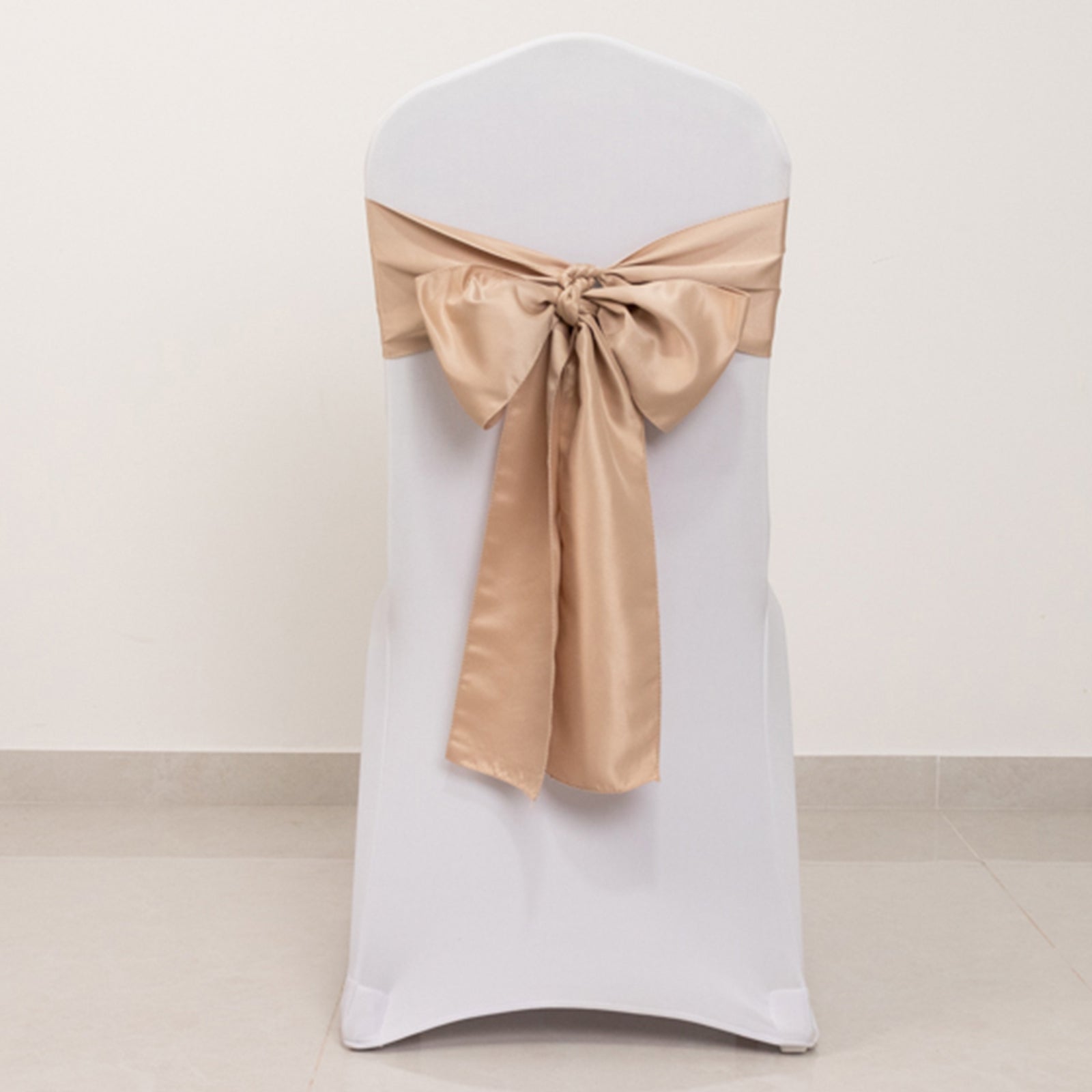 Nude satin chair sash bow on a white chair.